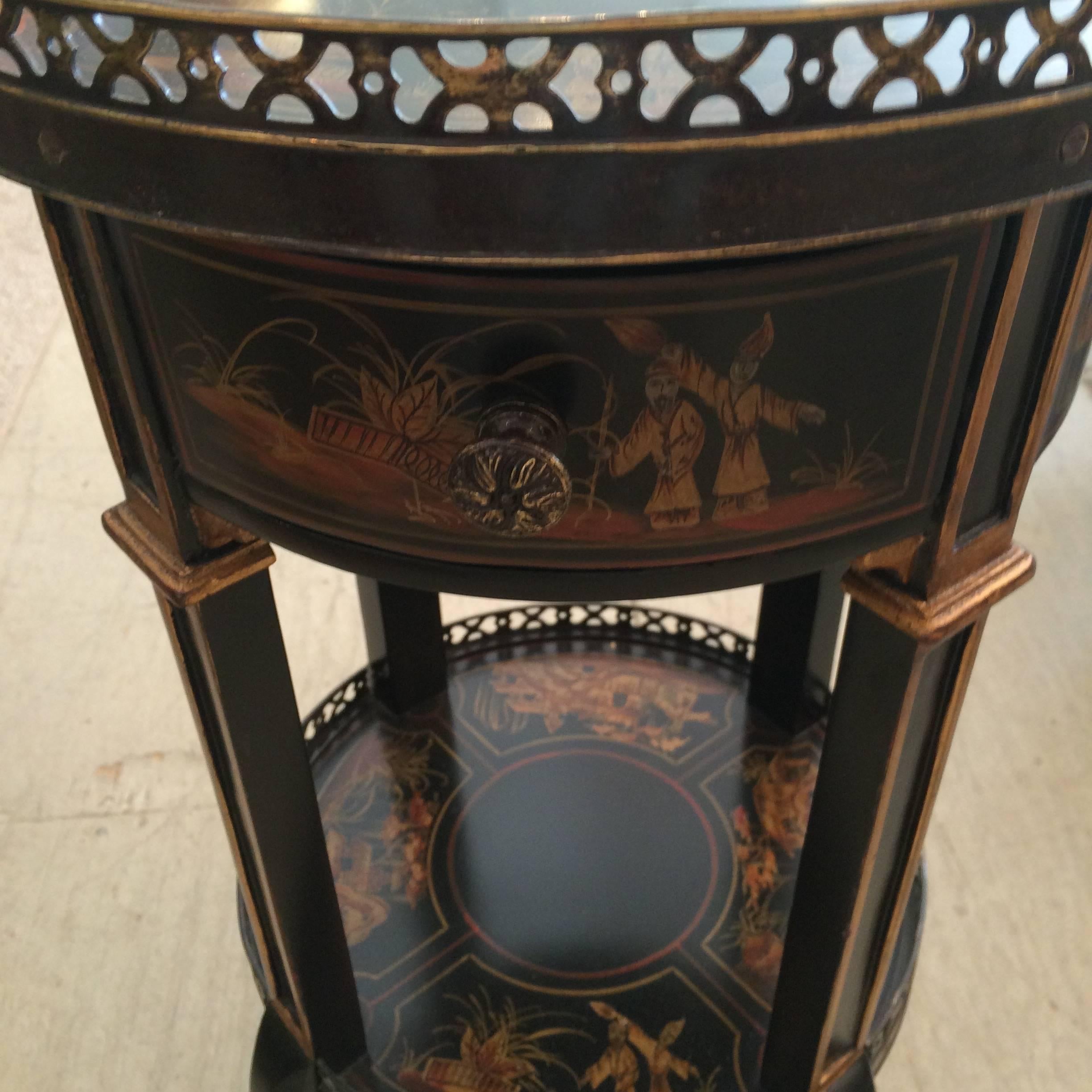 Lovely round two-tier side table by Theodore Alexander in black and gold with bronze galleries around the top and bottom surfaces and mounts on the feet. Single drawer. Bottom tier is 11.25