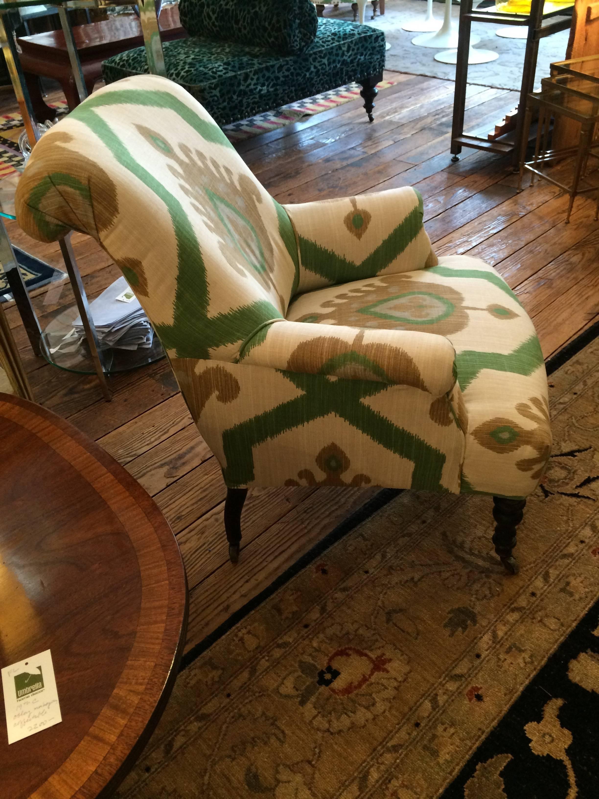 Wonderful shape and scale club chair with mahogany turned feet at the front, straight legs at the back, all on brass casters. Fabric is cream, green and light brown bold but neutral Ikat by Thibaut.