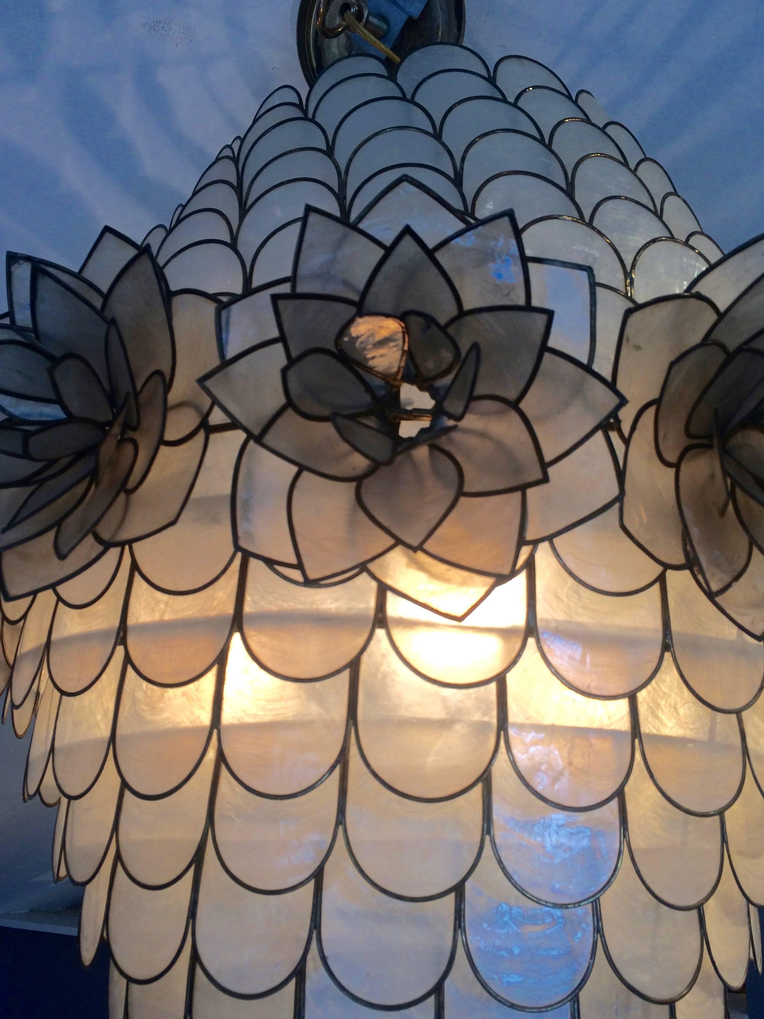 Impressive in scale and very stylish abalone shell capiz style chandelier adorned with a row of shell flowers around the periphery of the widest section.
Takes three 60 watt bulbs.

OGT