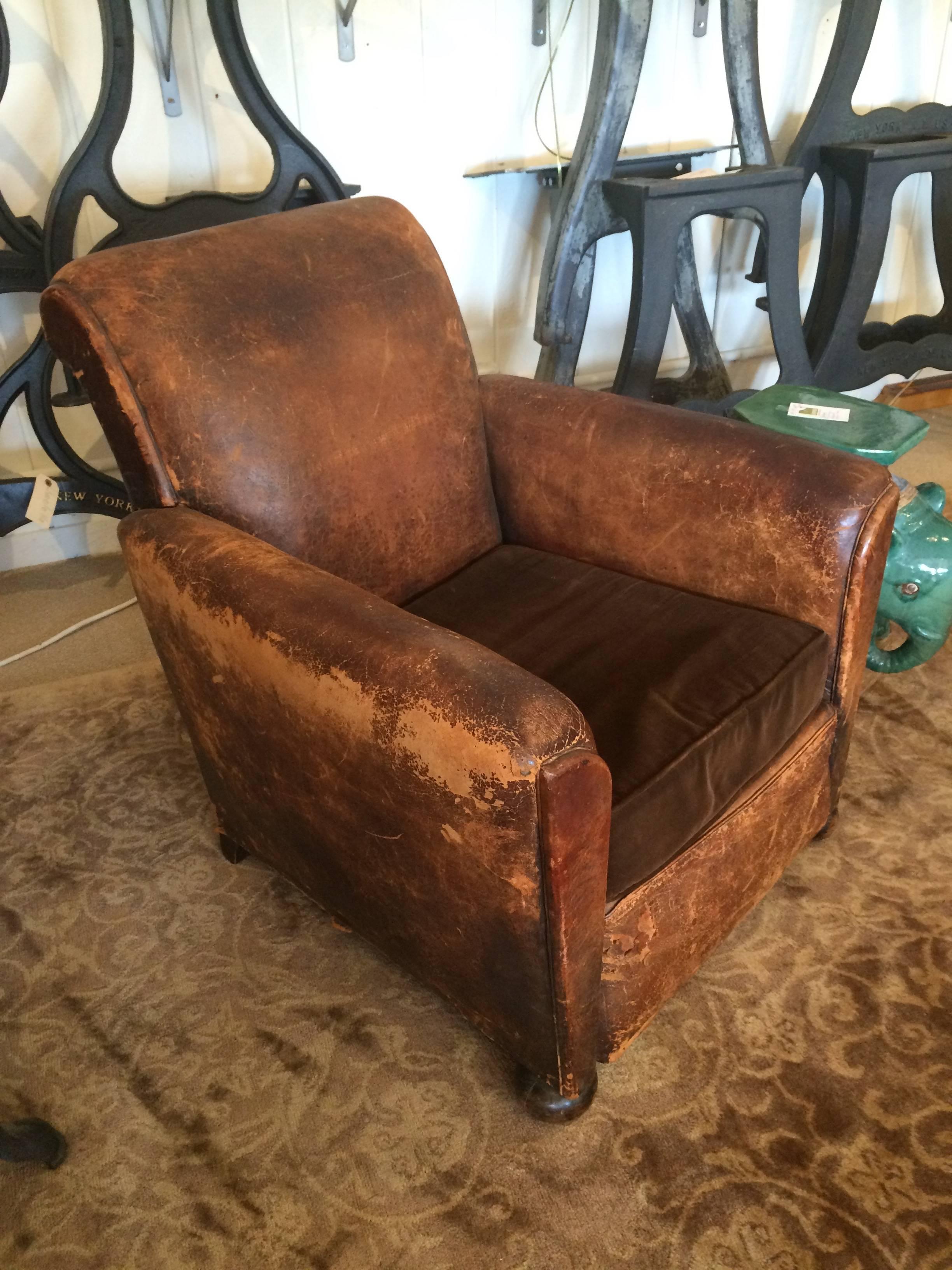 Wonderful vintage brown leather club chair from France, apartment sized, with richly distressed leather, bun feet on the front, and big dark nailheads around the back. Seat cushion is comfy brown velvet.