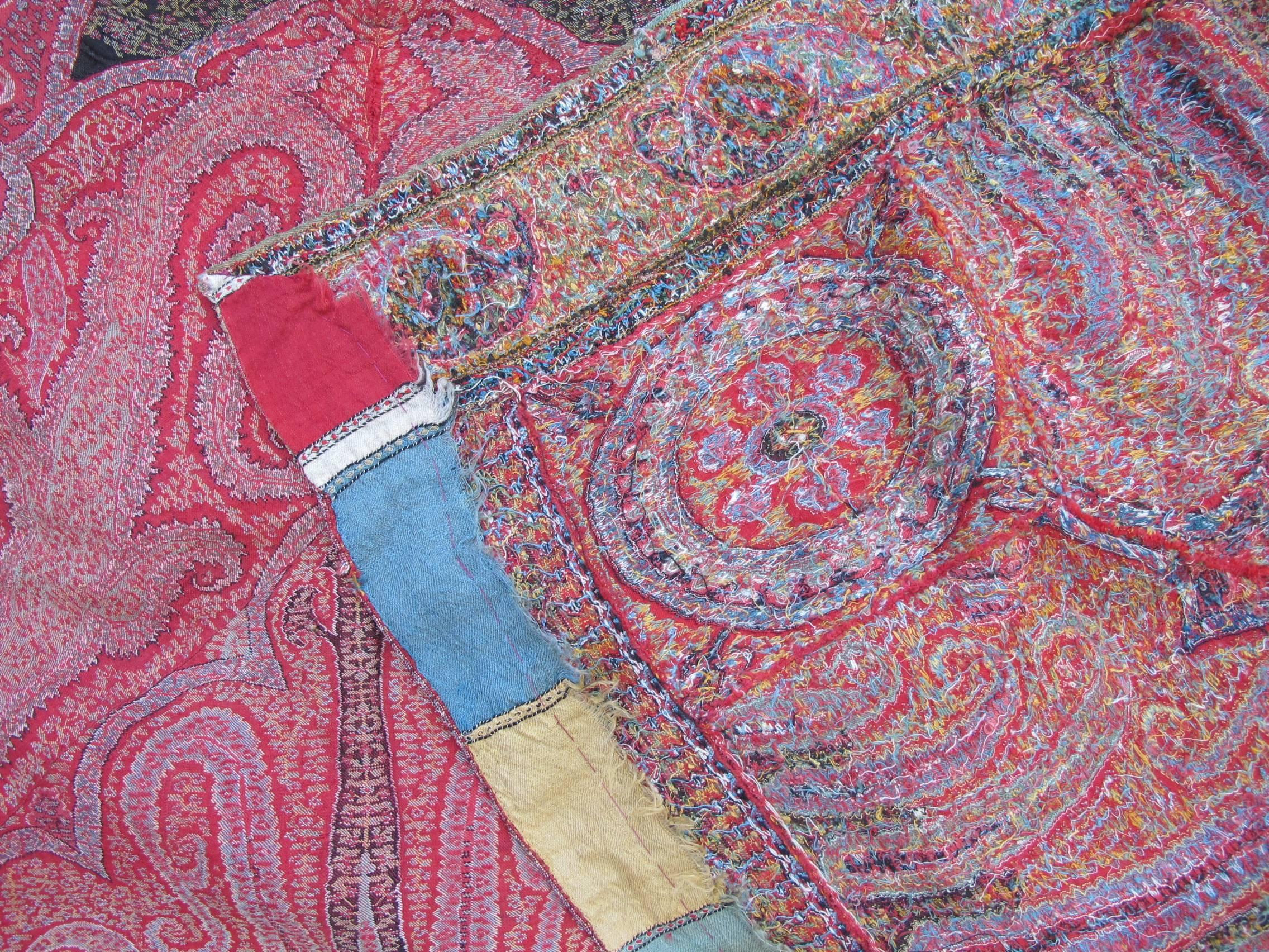 Ein Paisley-Schal, ca. 1860, hergestellt nach der Rafugars-Methode, bei der die handgewebten Stücke in mühevoller Handarbeit zusammengenäht werden, um das Paisley-Motiv zu formen. Vorwiegend in warmen Rottönen mit einem schwarzen Zentrum.