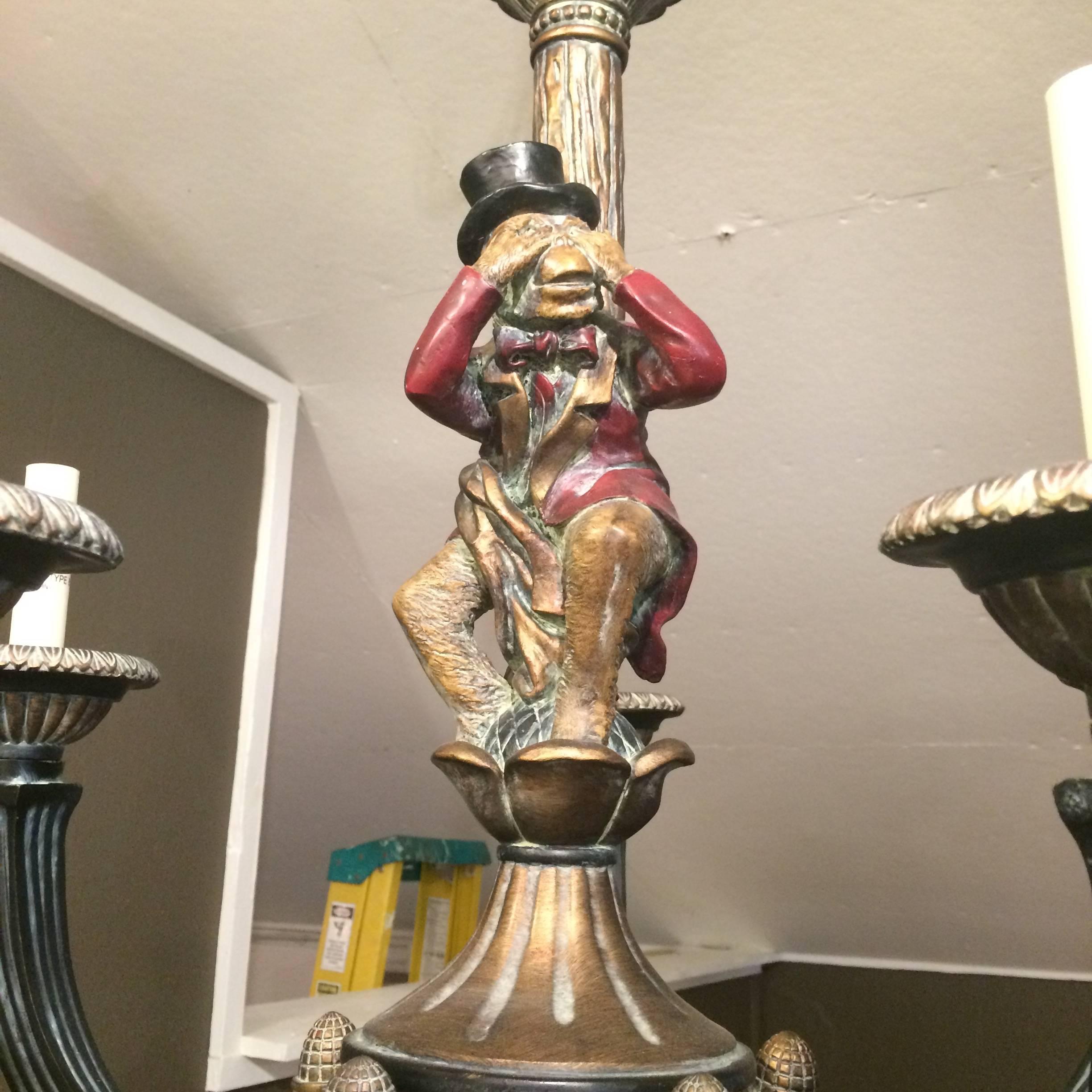 Wonderful wooden chandelier painted black, gold, and a little bit of warm red, having four arms (60 watt each) and a central adorable monkey in top hat, covering his eyes.  Comes with leopard patterned shades for each bulb.

KMc