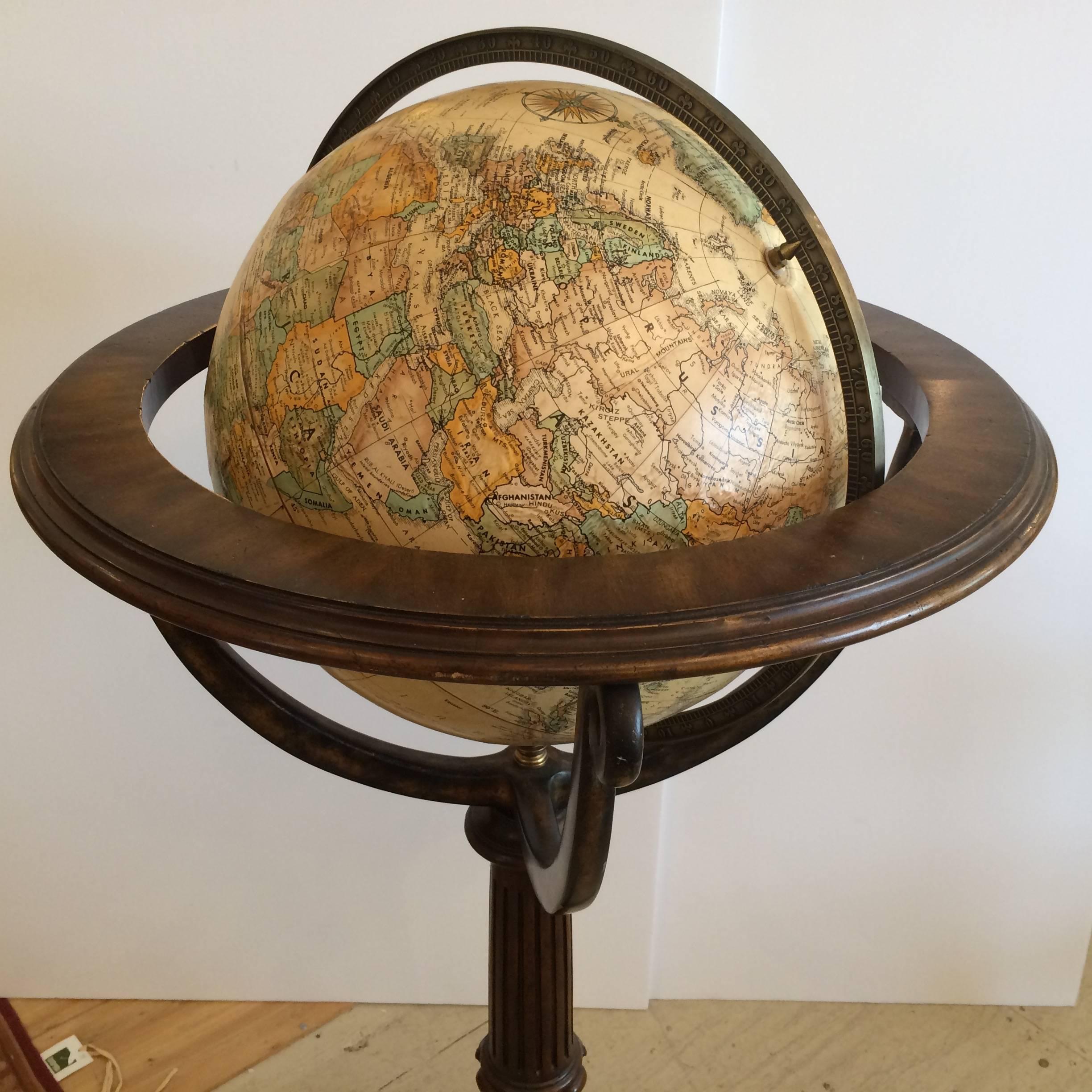 Beautifully made standing globe with rich carved wood three legged stand, having brass adornments and a warm golden aged globe that rotates.