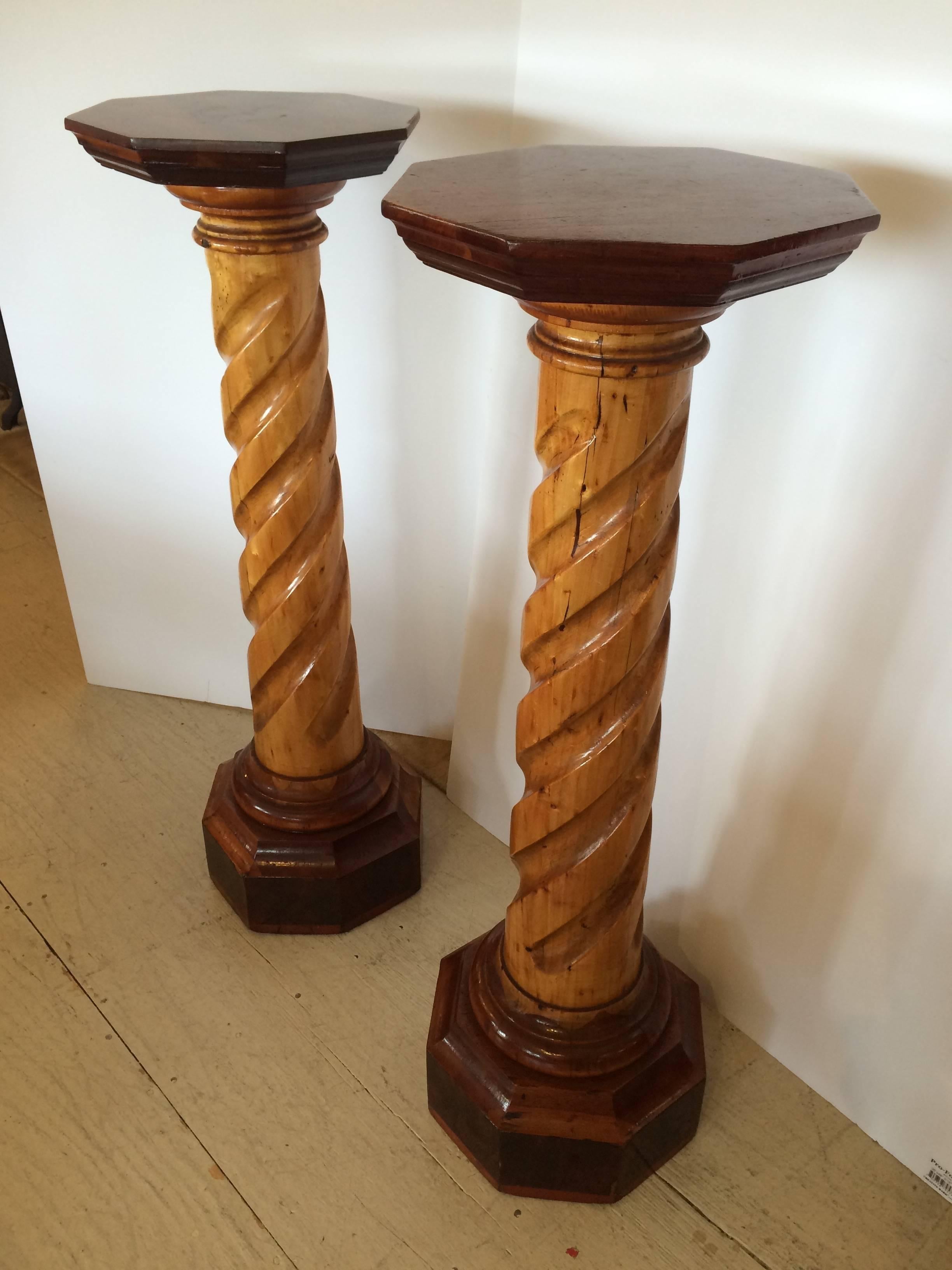 Stunning pair of carved wood pedestals having spiral carved design on the honey maple colored columns and a richer brown mahogany octagonal shaped top and bottom.

GG.