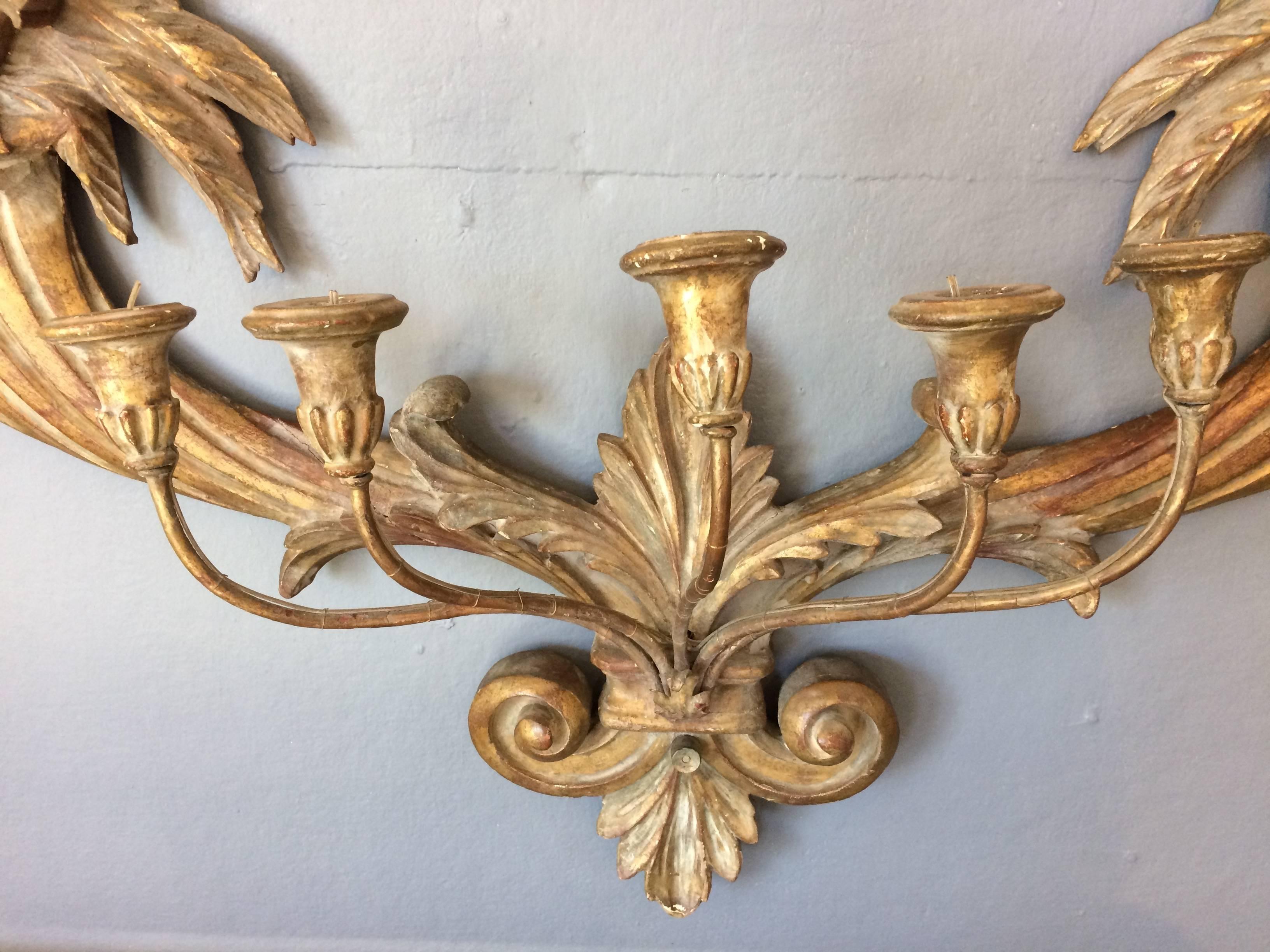 Large antique carved giltwood wall sconces having wonderful foliage and fruit on either end and five candle arms. Looks like it was once electrified as there are vestiges wire.