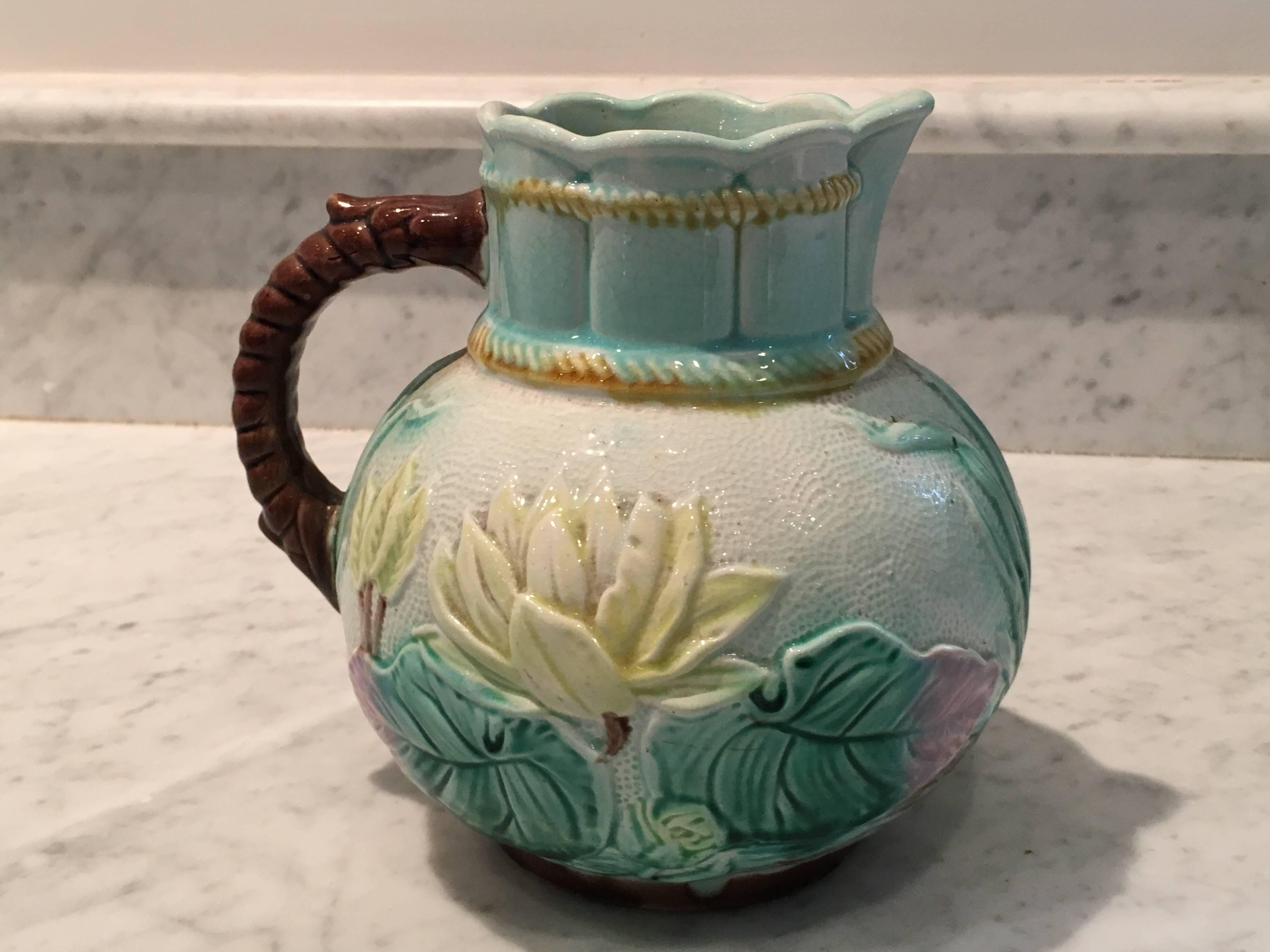 Beautifully detailed water lilies decorate this antique Majolica pitcher in shades of turquoise, yellow and pink. Turquoise interior. Signed/marked in brown paint on bottom.