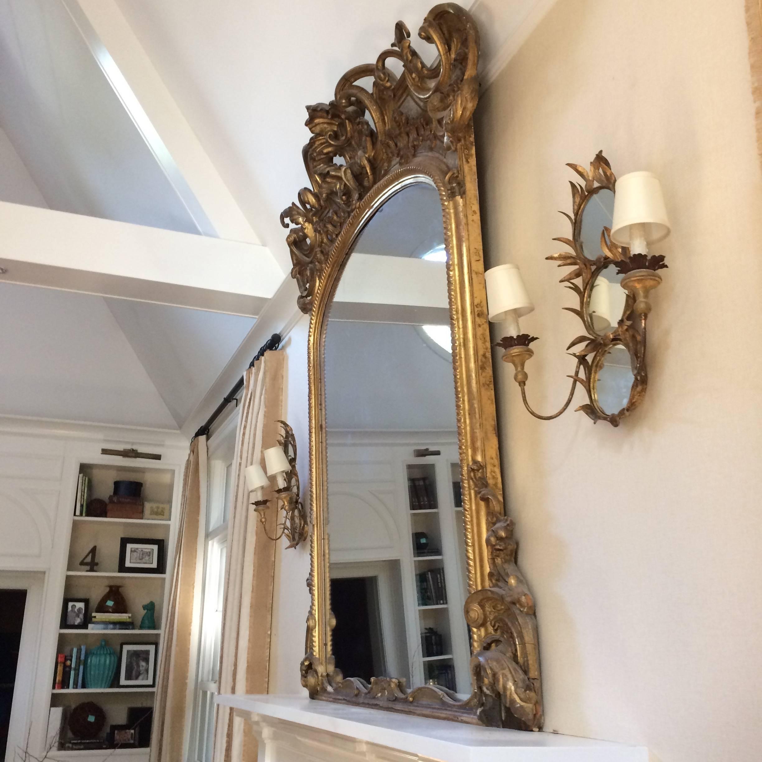 One of a kind theatrical and impressively huge antique giltwood mirror with ornate carving around the top and bottom corners.