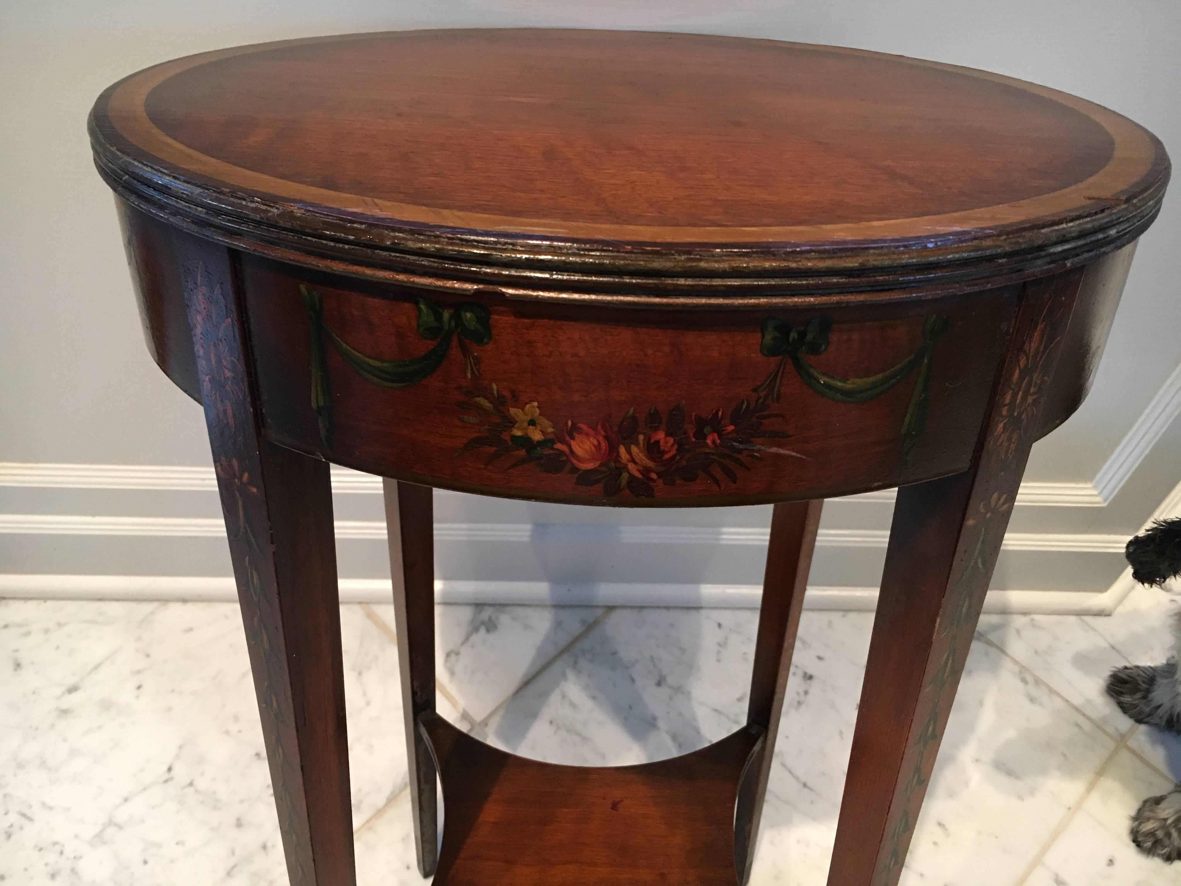 Charming oval mahogany side table with hand-painted decoration. Ribboned swags and flowers encompass the table's apron, and bell flowers run down each table leg.
 