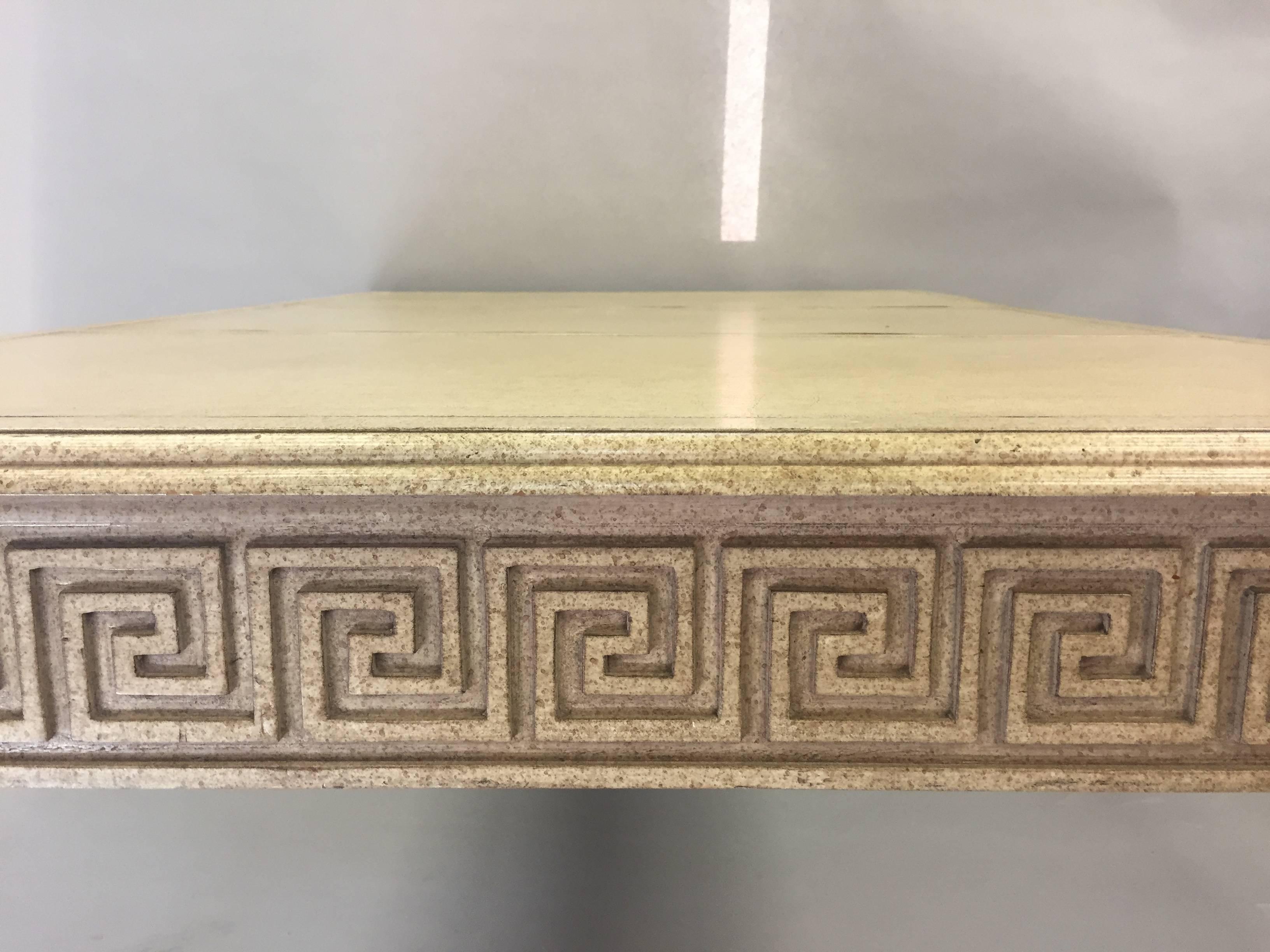 Glamorous Hollywood Regency style carved and painted writing desk having handsome figural lion heads on the corners and stylish Greek key decoration all the way around the periphery so beautiful from every angle. Top is a cream leather with embossed