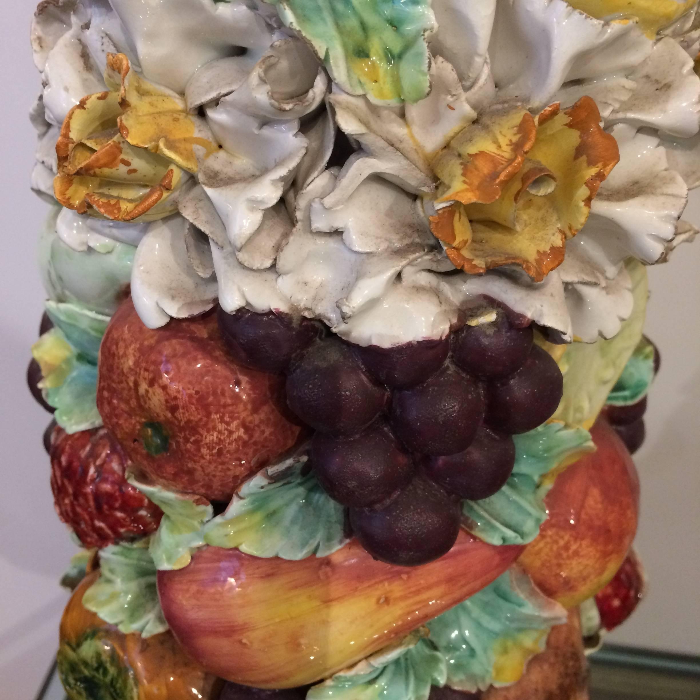 Eye-catching richly intricate topiary sculptures having a wonderful mixture of ceramic flowers and fruits in a scrumptious palette of orange, eggplant, cream, green and yellow.