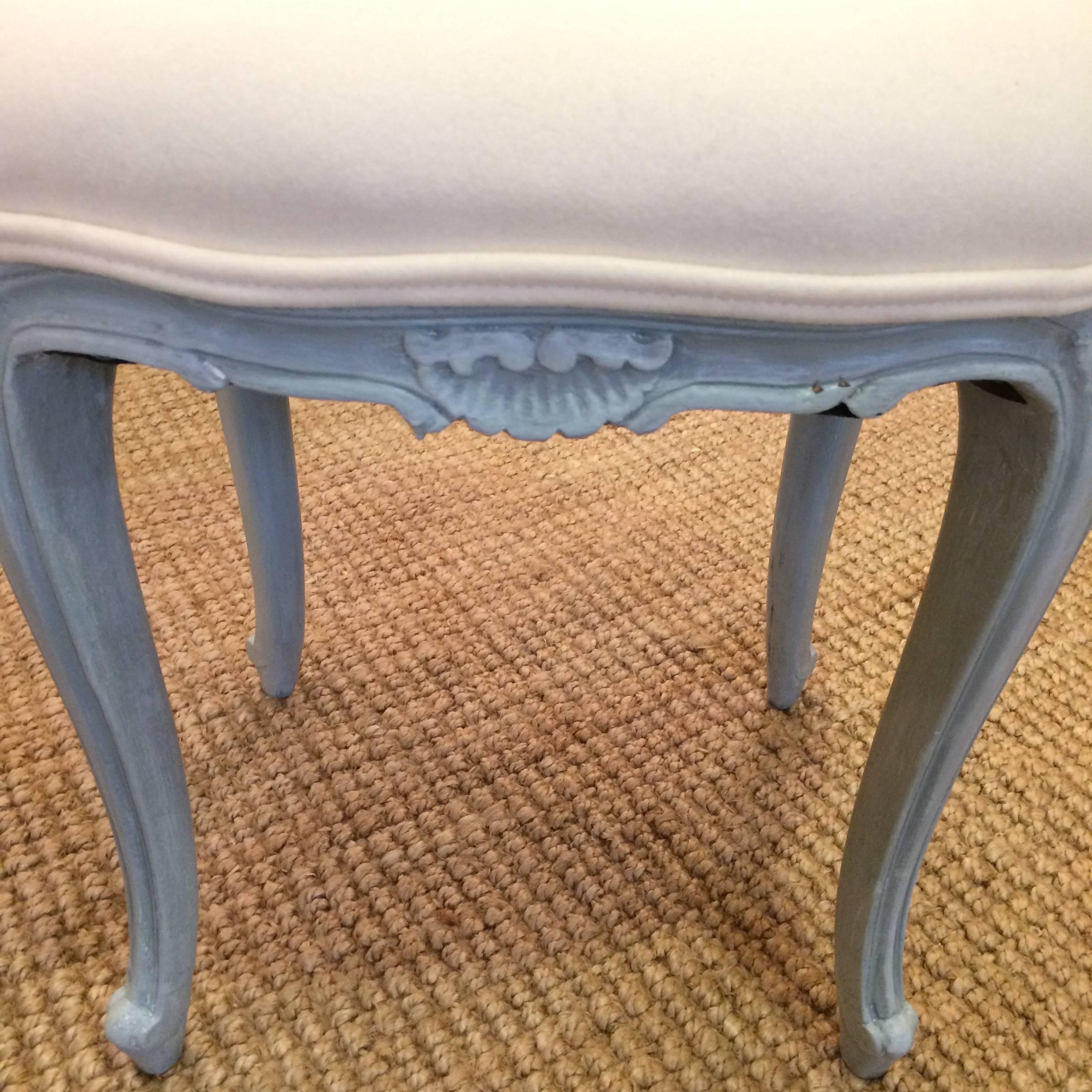 Two lovely stools or small ottomans having grey blue painted bases with pretty carved shell decoration and cabriole legs, newly upholstered in off-white wool cashmere.