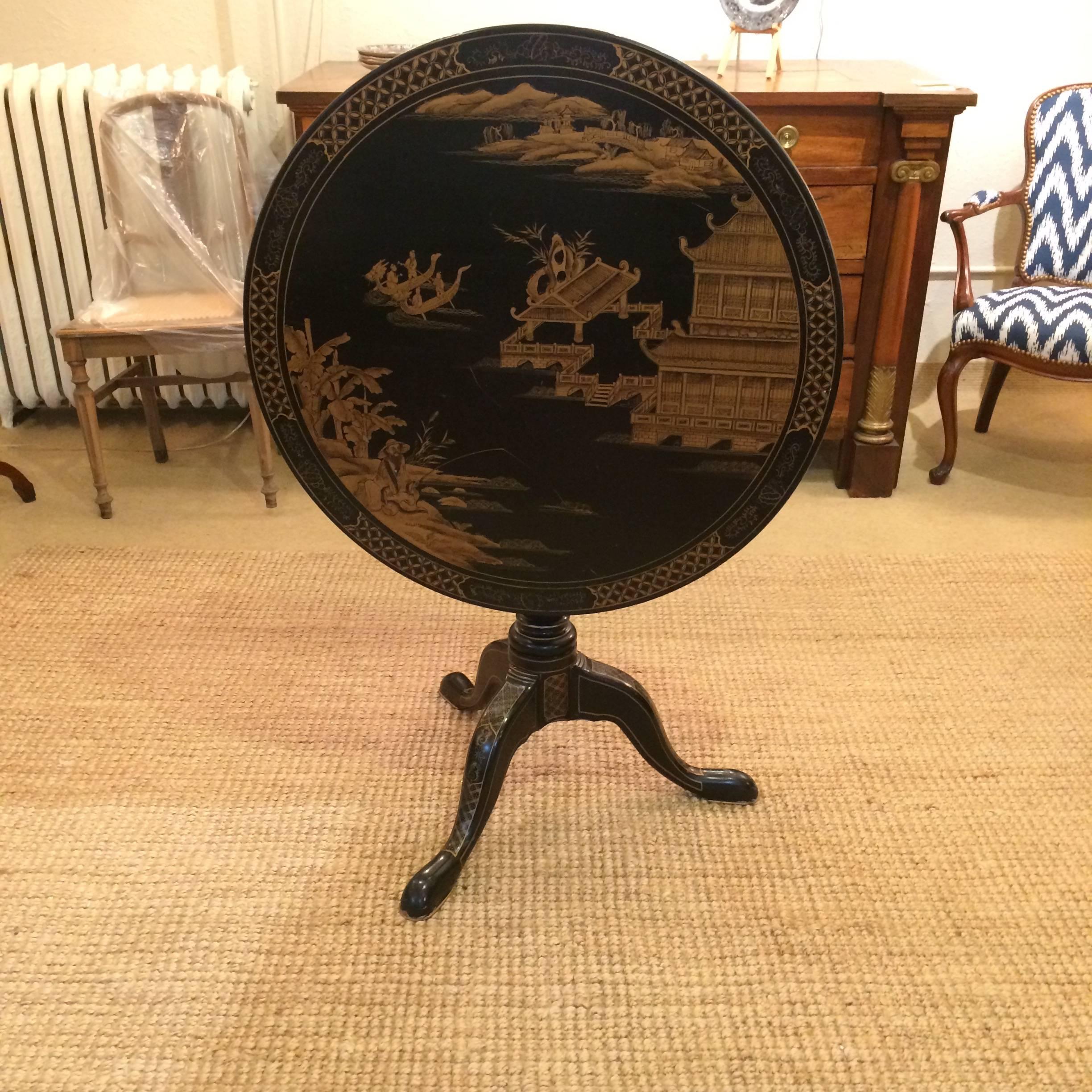 Beautiful black and gold chinioserie style hand-painted round table with flip-top surface and lovely tripod base.