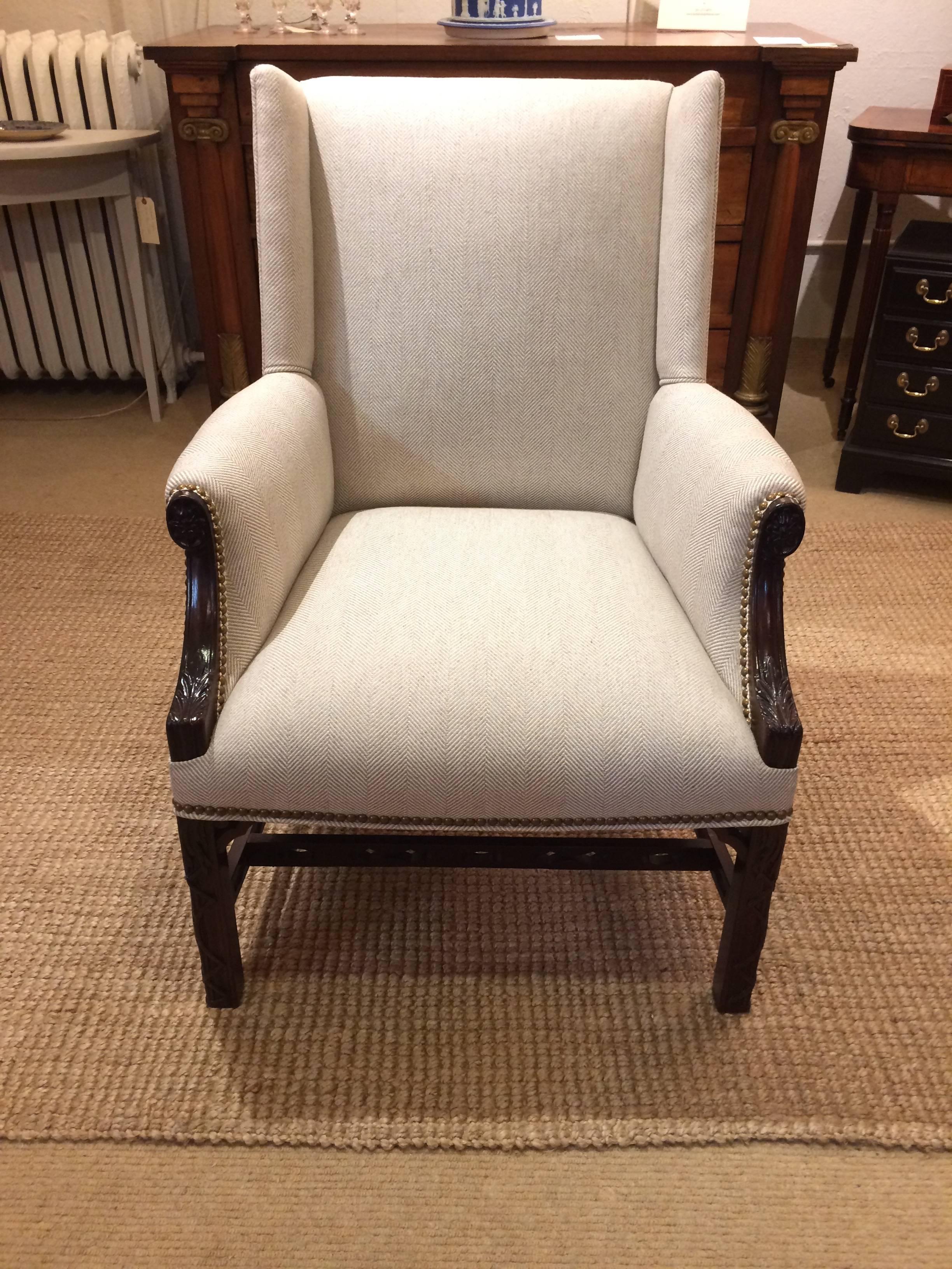 Classic antique 19th century English club chairs with carved mahogany having cameo flowers and acanthus leaves and newly upholstered in handsome tone on tone herringbone finished with matte brass studs.