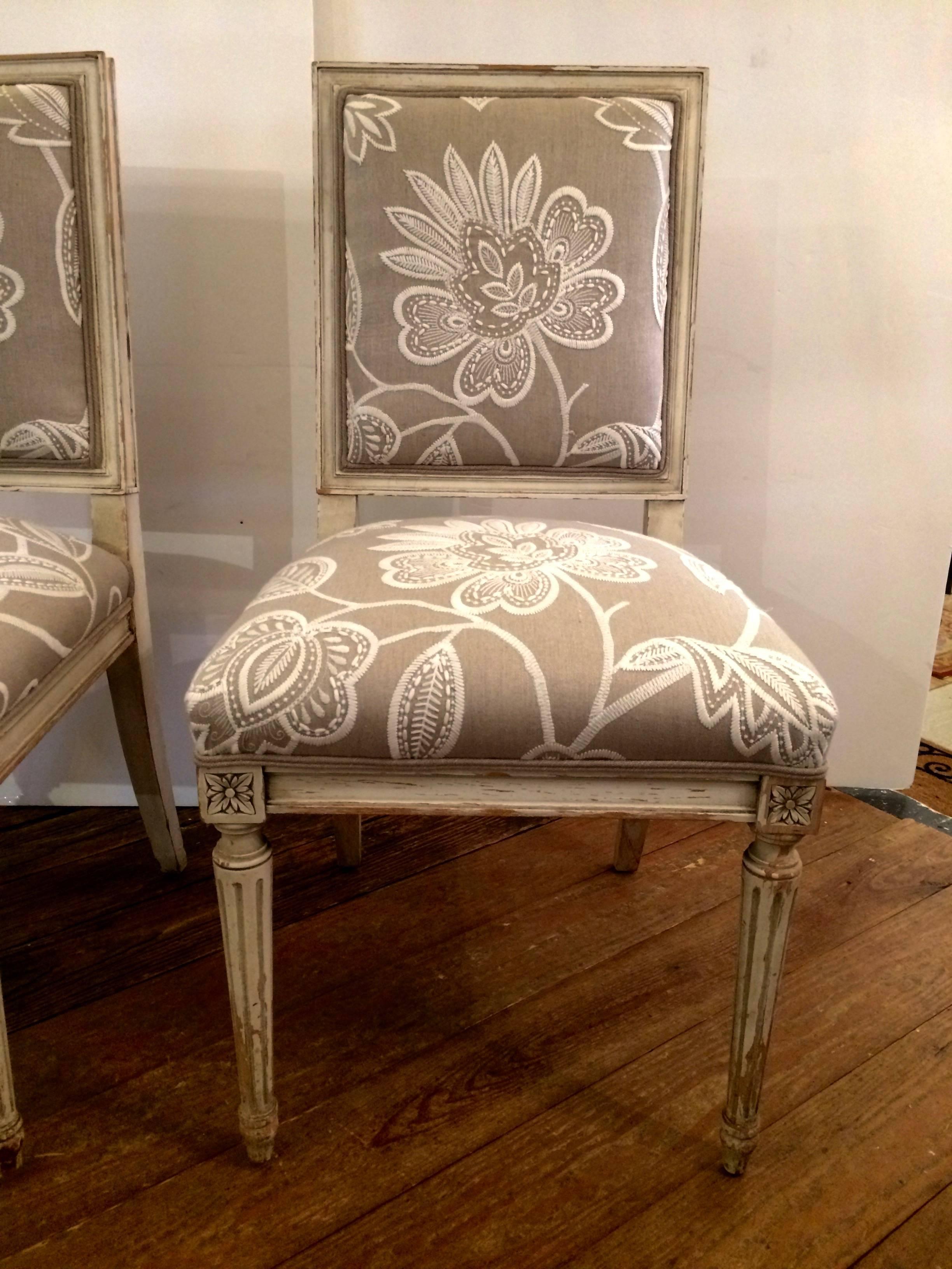 Classic French style side chairs with off-white antiqued painted carved wood frames and new taupe and white Anna French upholstery. (Thiebeau) Chippy paint is intentional for a casual slightly weathered aged look.