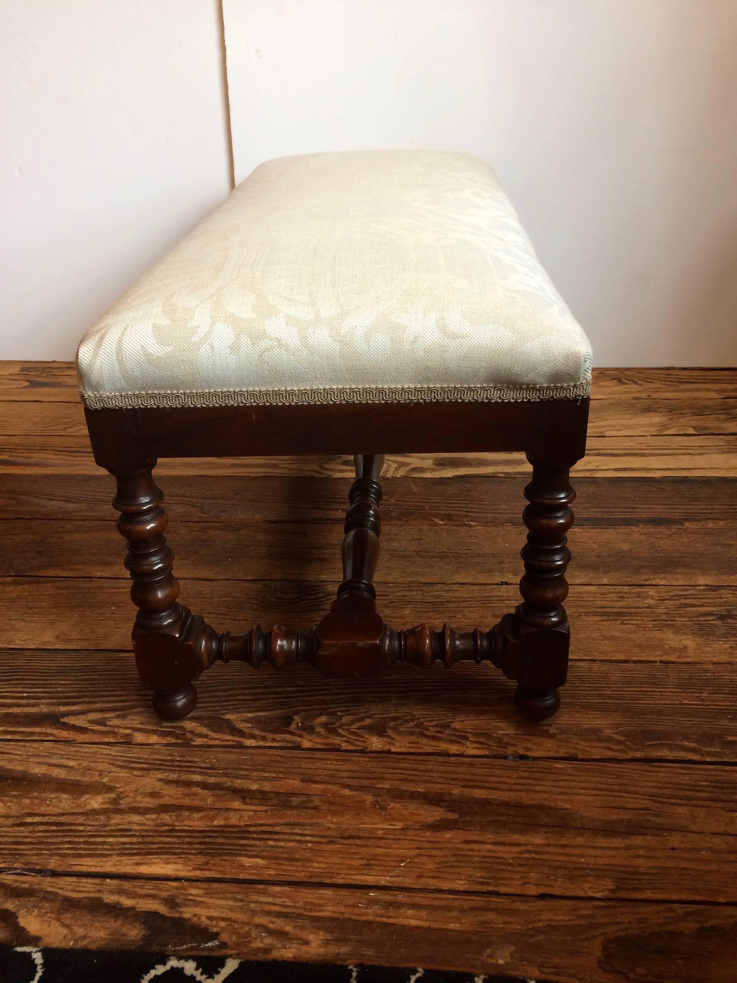 Classic traditional bench having mahogany barley twist legs and stretcher, newly upholstered in a neutral fortuny style pattern fabric.