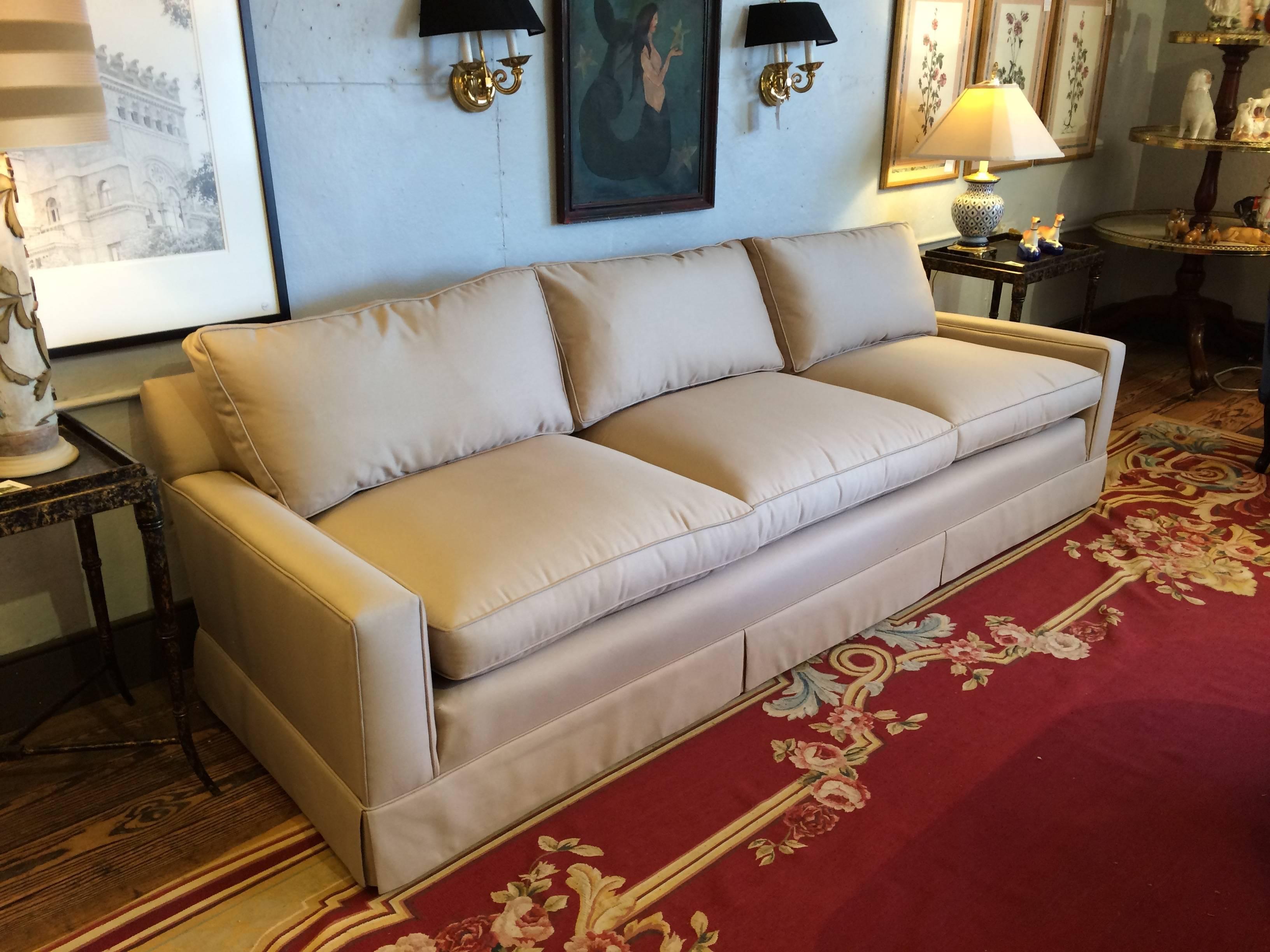 Beautifully made custom sofa, quite long and sleek in stature, having three-seat cushions and three back cushions, upholstered in a neutral light tan solid fabric.


  