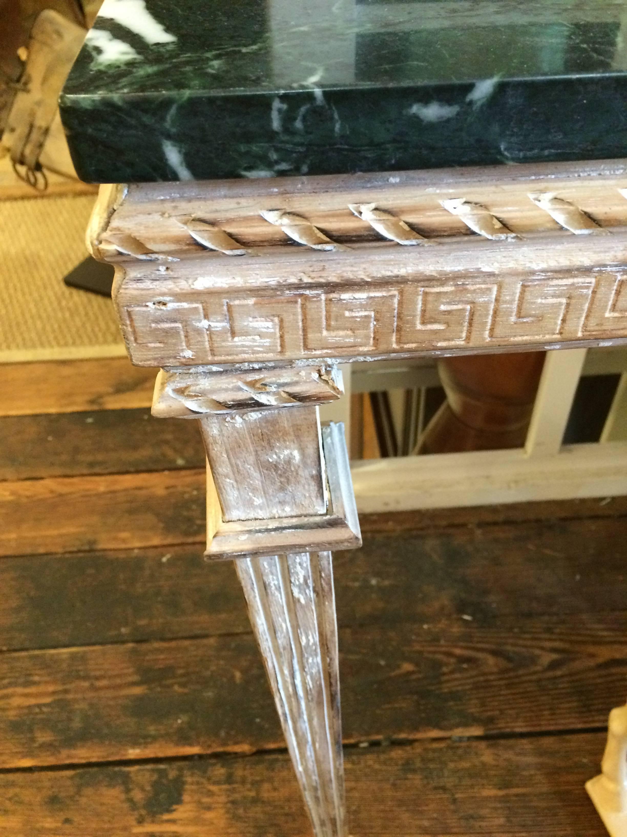 Lovely pair of console tables having carved distressed painted wood bases with a Greek key motife around the edge, topped with elegant black marble.

Note: Will sell individually.