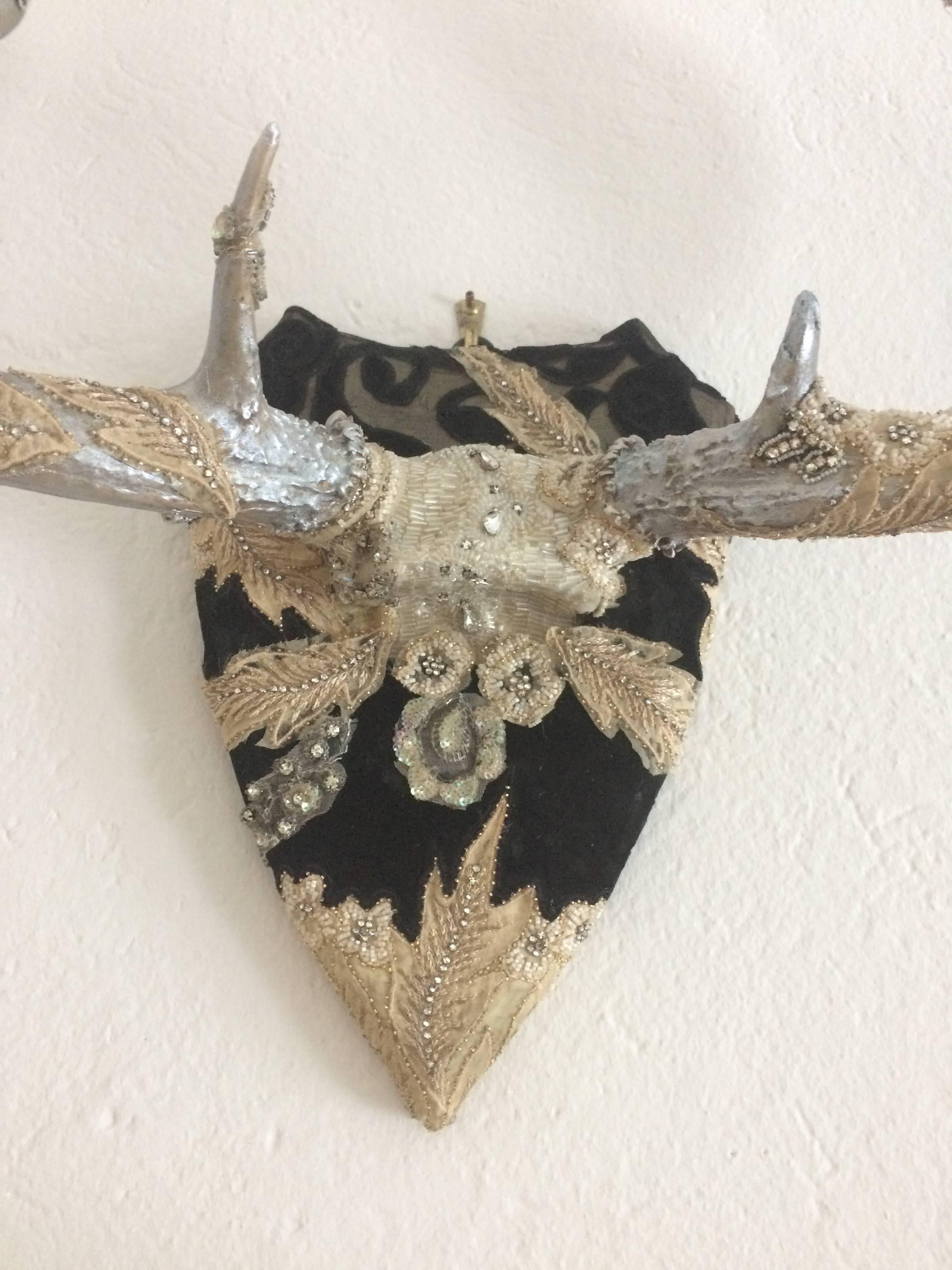 Magical mixed-media wall art beginning with a pair of branch like antlers, transformed into a romantic wall sculpture with silver leaf and be jewelry antlers and a shield covered in velvet applique, lace, rhinetones and other vintage embellishments.