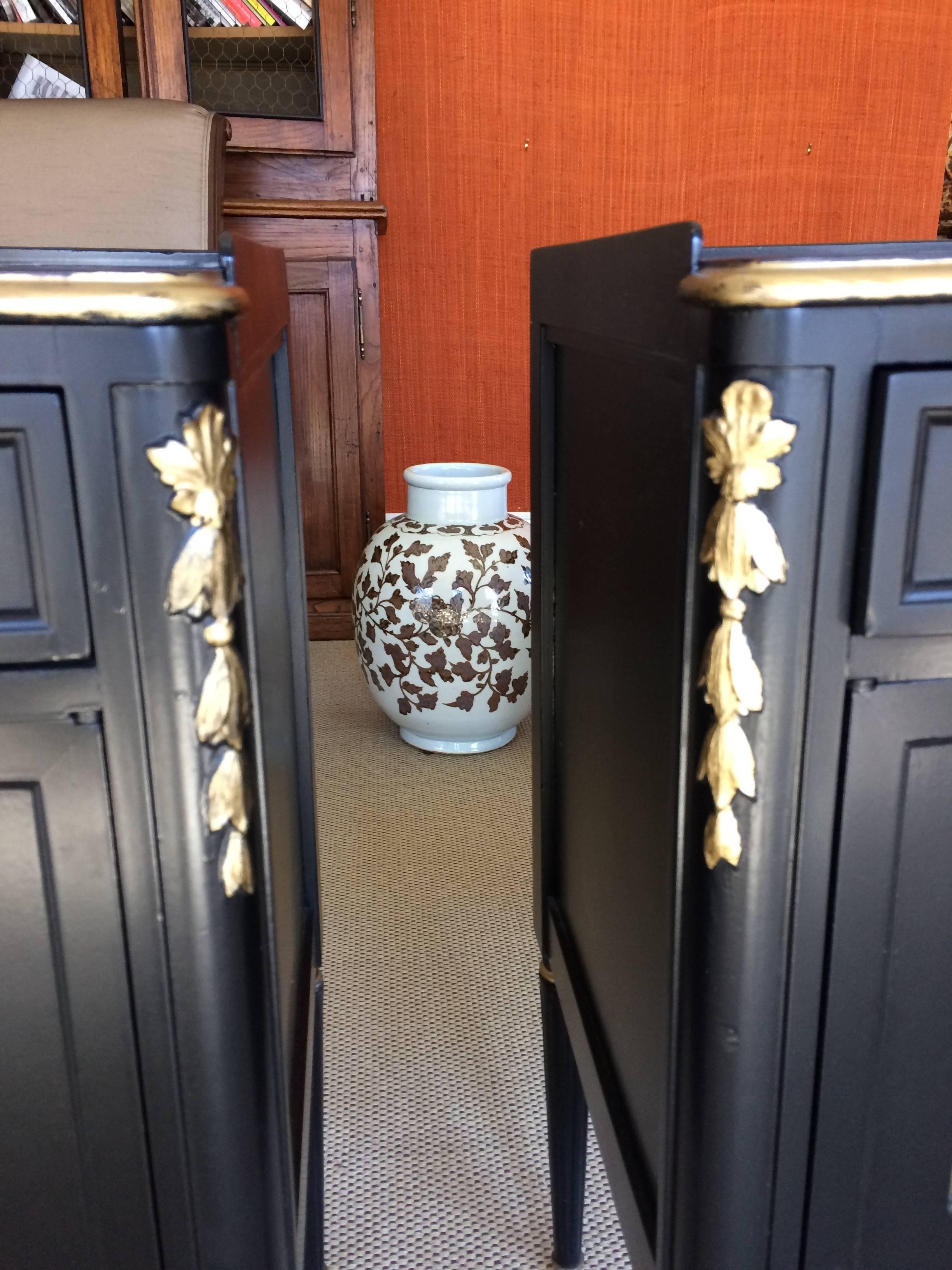 Two matching black and gold nightstands or end tables having single drawer and two-panel doors that open to storage within. Hollywood Regency style gold decoration on the front edges and unusual open gold mesh rectangular openings in the panels.