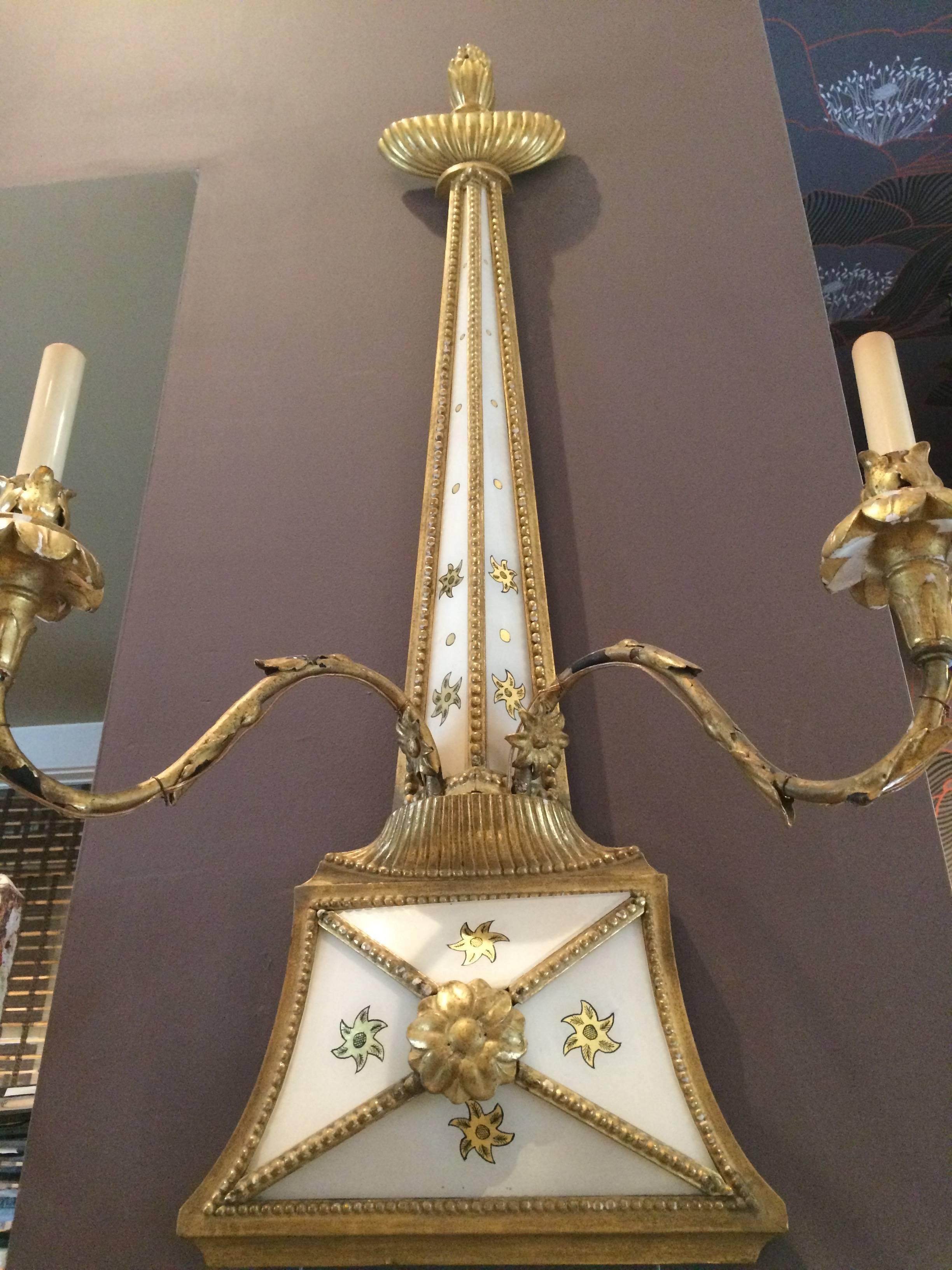 Unusual and grand pair of candle sconces with white background reverse painted with gold stars and having giltwood decoration.  Wired for electricity. Measures: Base is 13 W.