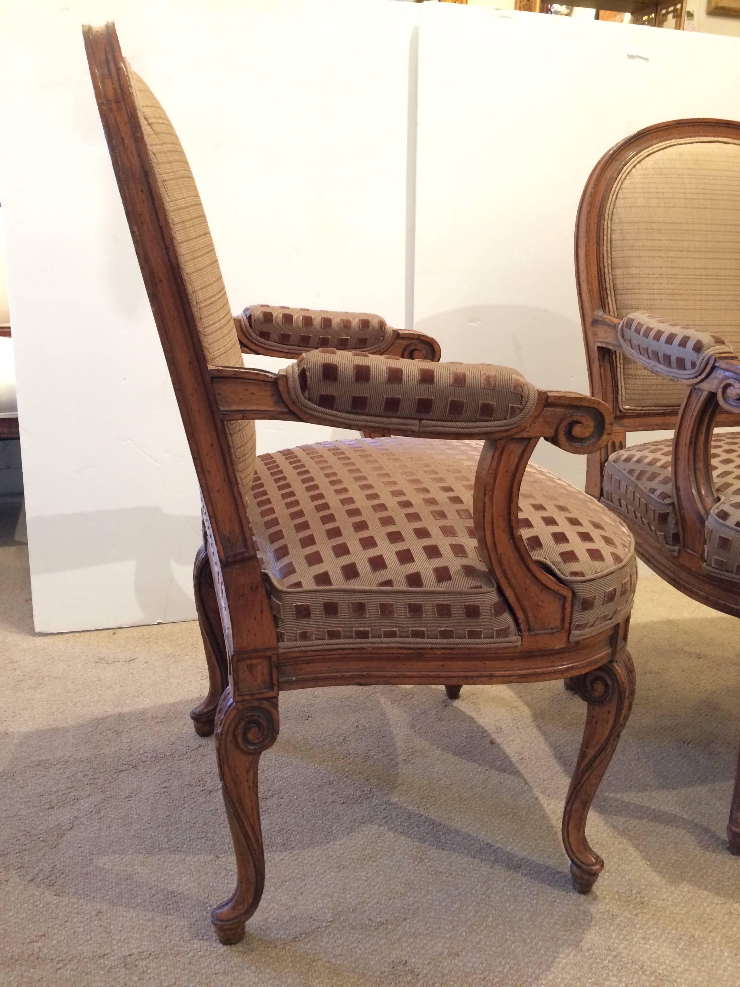 Two handsome carved walnut armchairs with cabriole legs and comfortable roomy seats and backs, imaginatively upholstered with two complimentary aubergine and khaki cut velvet fabrics on the front, and a striped silk on the back.