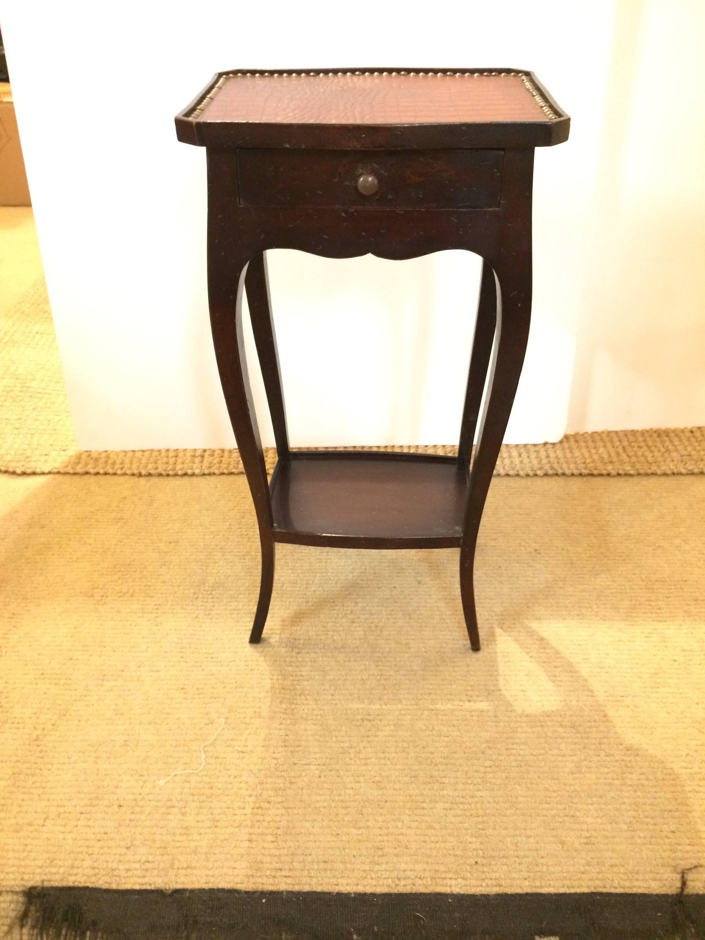 Masculine Italian ebonized walnut side or end table having single drawer, lower tier with wooden gallery surround, elegant curved legs, and a smashingly stylish faux alligator top finished with nailheads.