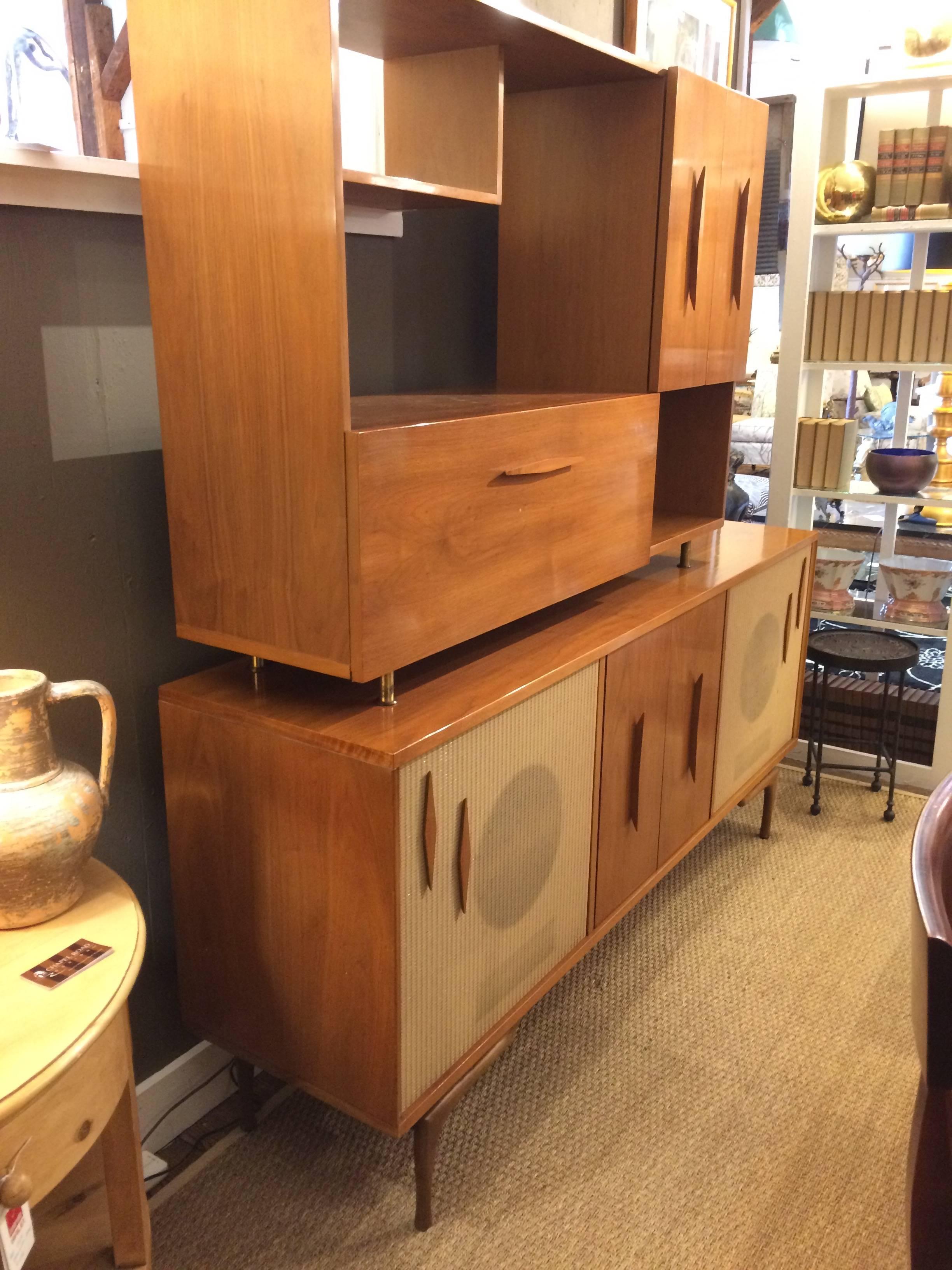 A totally mad men Mid-Century Modern two-piece walnut stereo cabinet and dry bar. Top piece has storage with adjustable shelf behind magnetized door panel as well as handsome open shelves. Bottom piece has pull down bar equipped with set of original