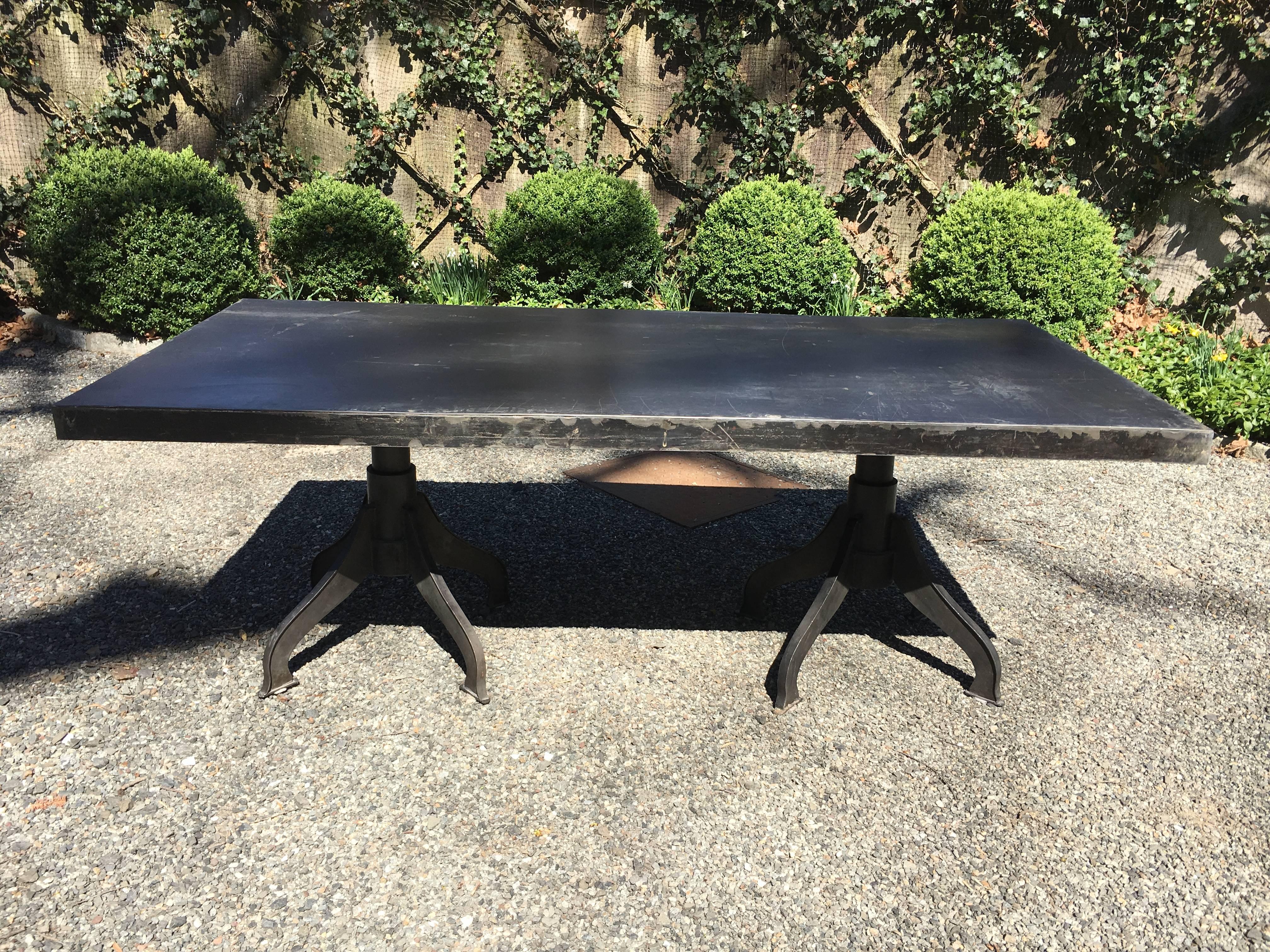 Amazing one-of-a-kind heavy steel dining or workspace table with Industrial steel legs. The rich patina of the surface shows scratches and sanded areas that add to its funky look. Legs bolt to top. No manufacturer markings. Measures: Apron is 2.75
