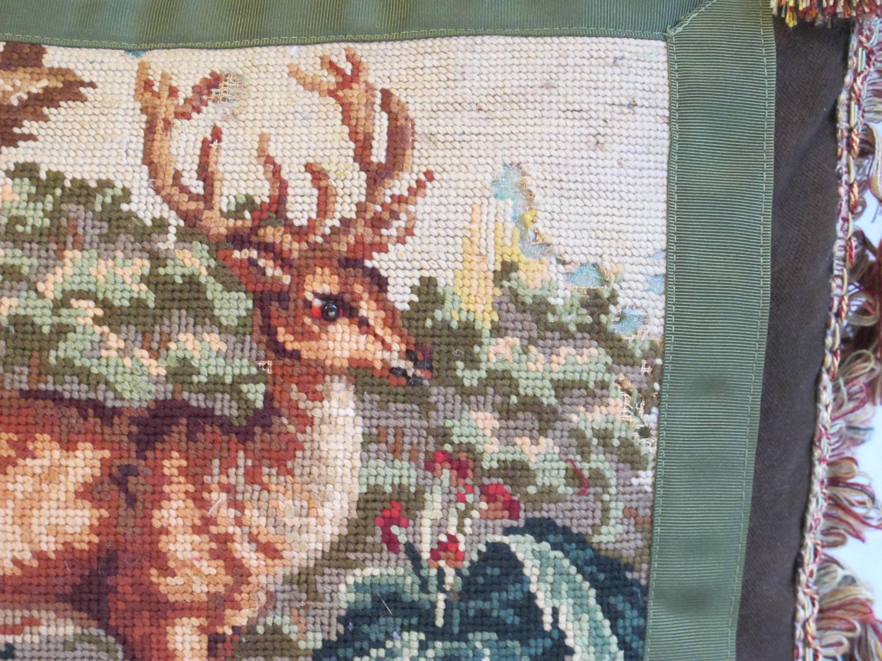 An early 20th century needlepoint tapestry depicting a forest scene with deer in gorgeous Autumn colors, embellished with vintage tassel trim and down insert is included.
Measures: 17