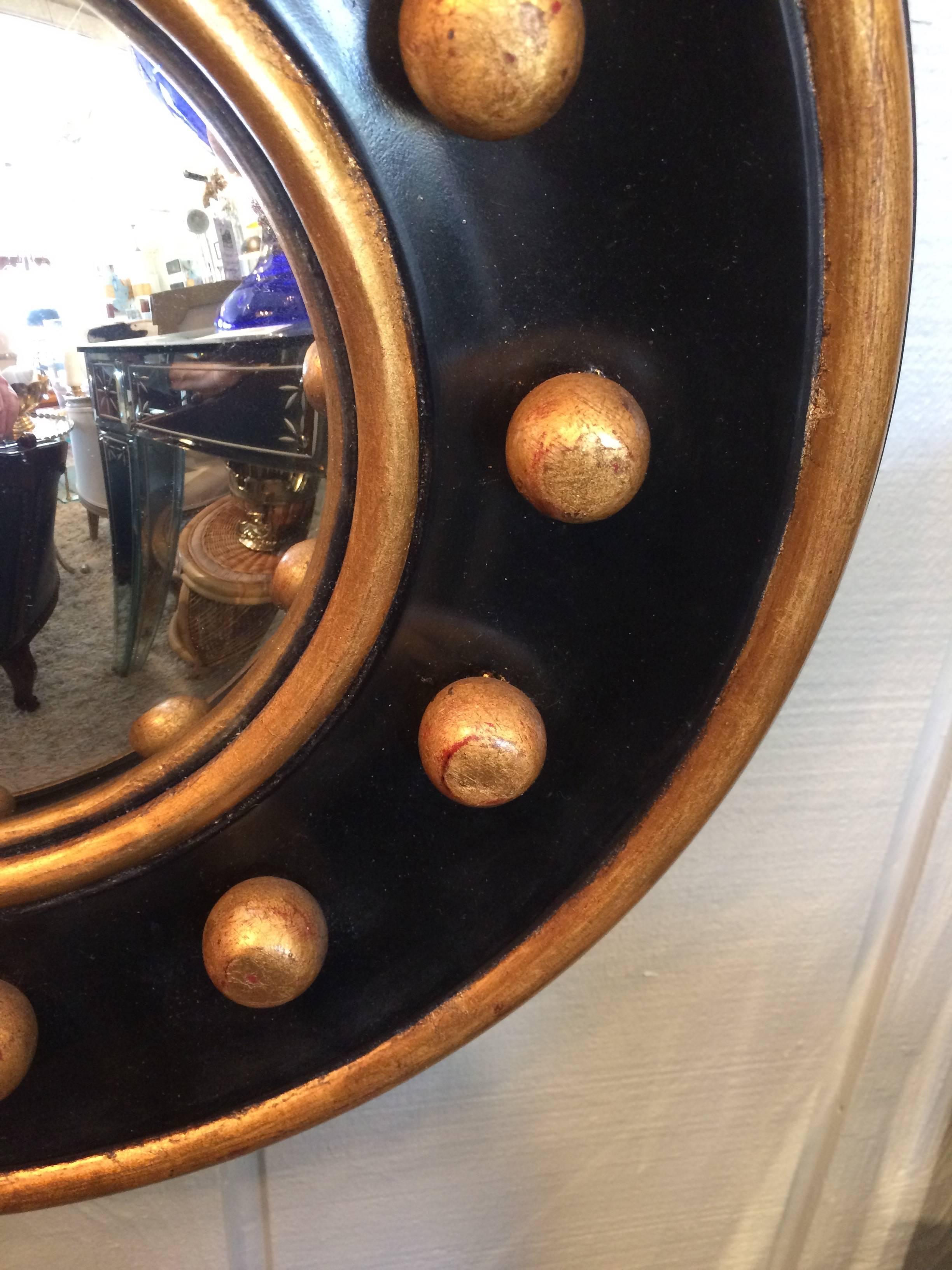 Powerful little wall mirror in a Regency style black and gold wood having three dimensional gold balls around a small convex mirror and gold border. You can tell by the back that it has age. Mirror itself measures 6.5 diameter.
