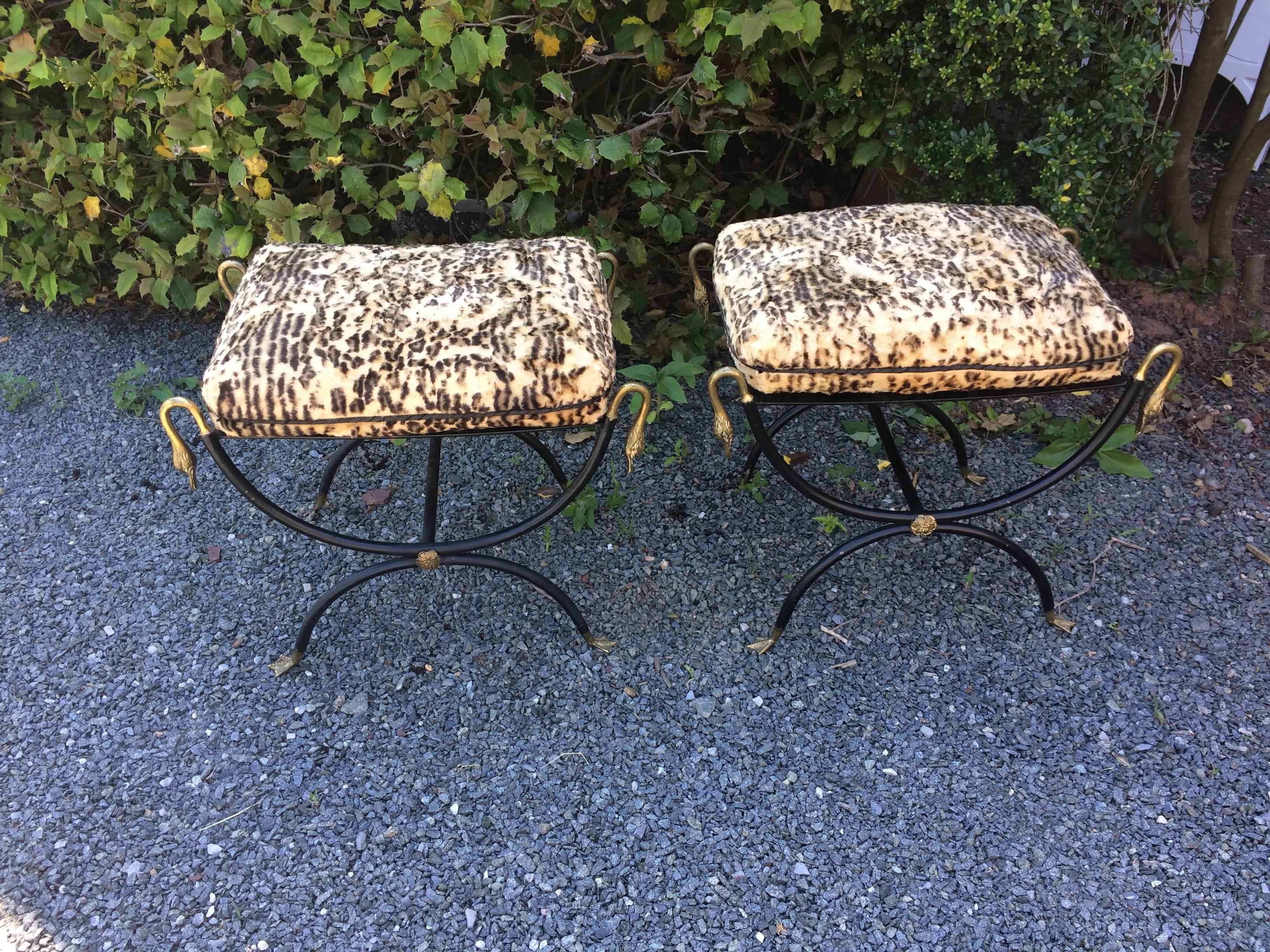 Two black iron neoclassical benches or ottomans having decorative bronze swan heads, central medallion and fabulous webbed feet, lattice criss cross tops, and original faux leopard cushions. (recommend reupholstering) Made in Italy on the underside.