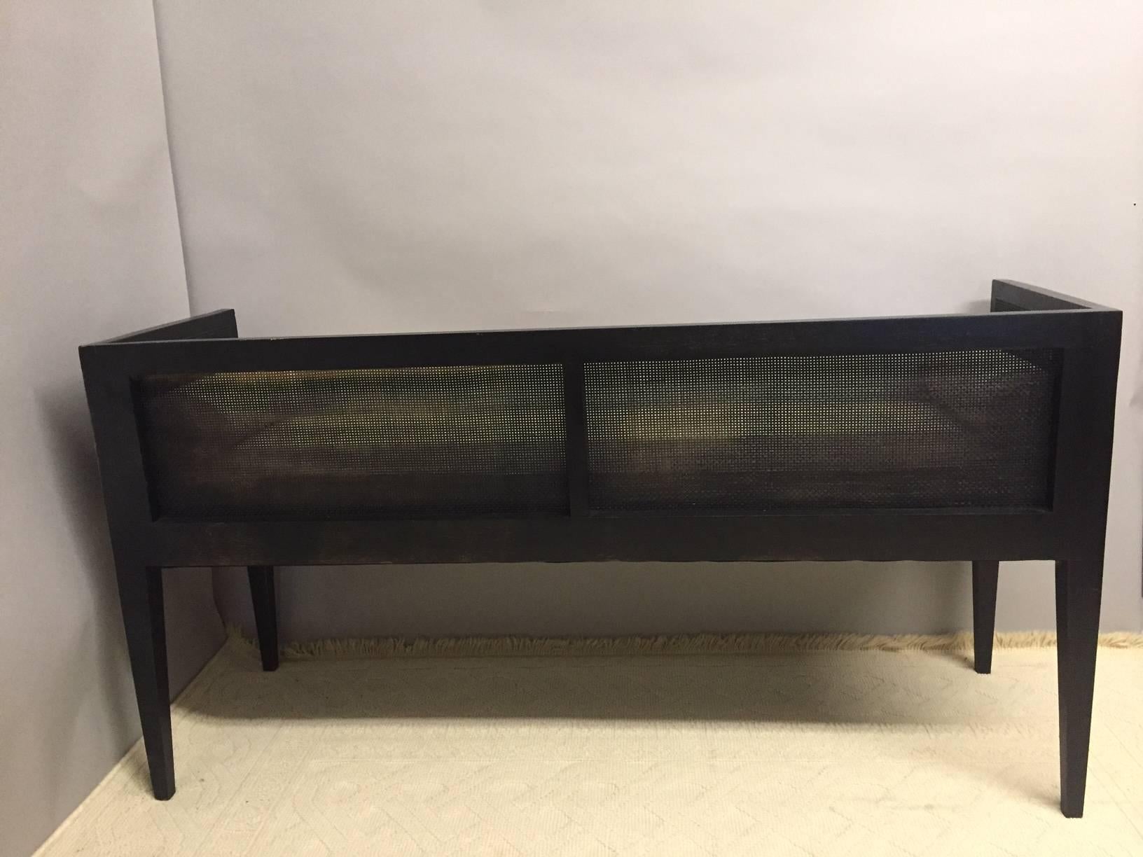 Traditional and handsome black wood and caned bench with handsome clean angular lines and newly upholstered in natural colored linen.