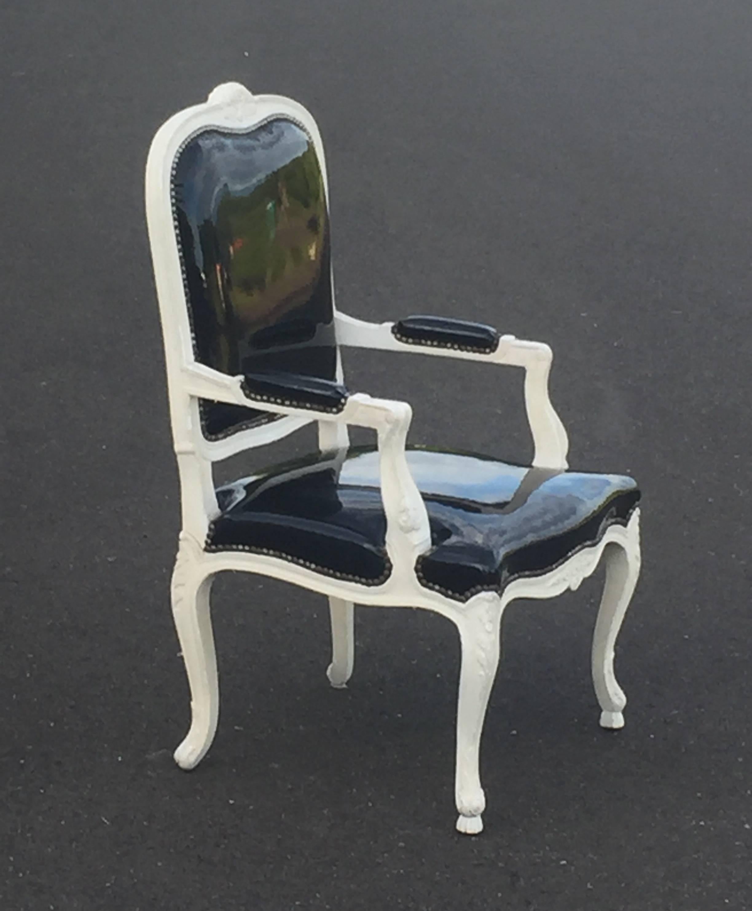 Louis XVI style chair having white carved painted frame in style of Billy Haines, glammed up with shiny black patent leather upholstery.