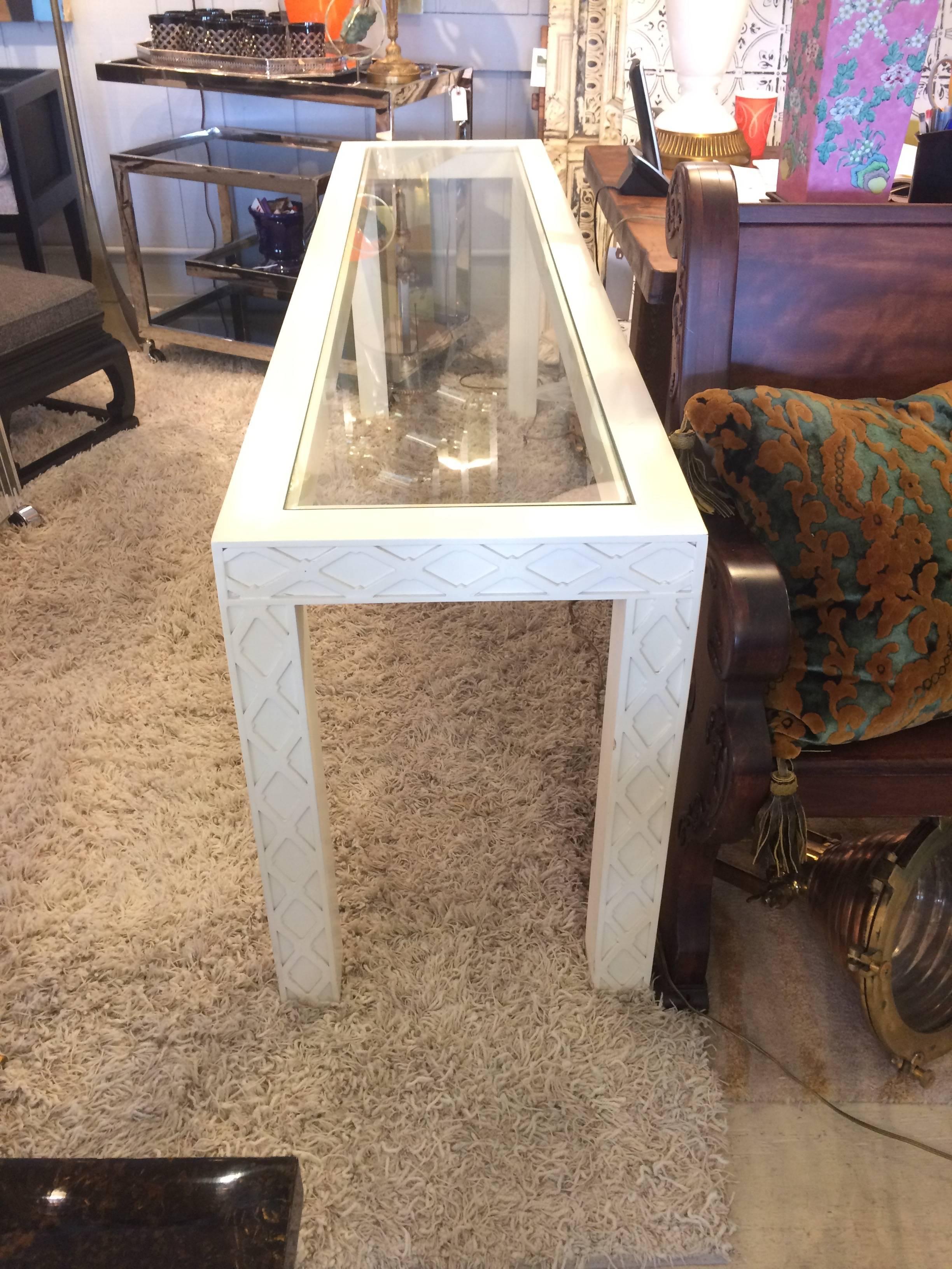 Parsons style Mid-Century Modern cream colored laquer console with decorative lattice style criss cross design around the edges. Glass top.