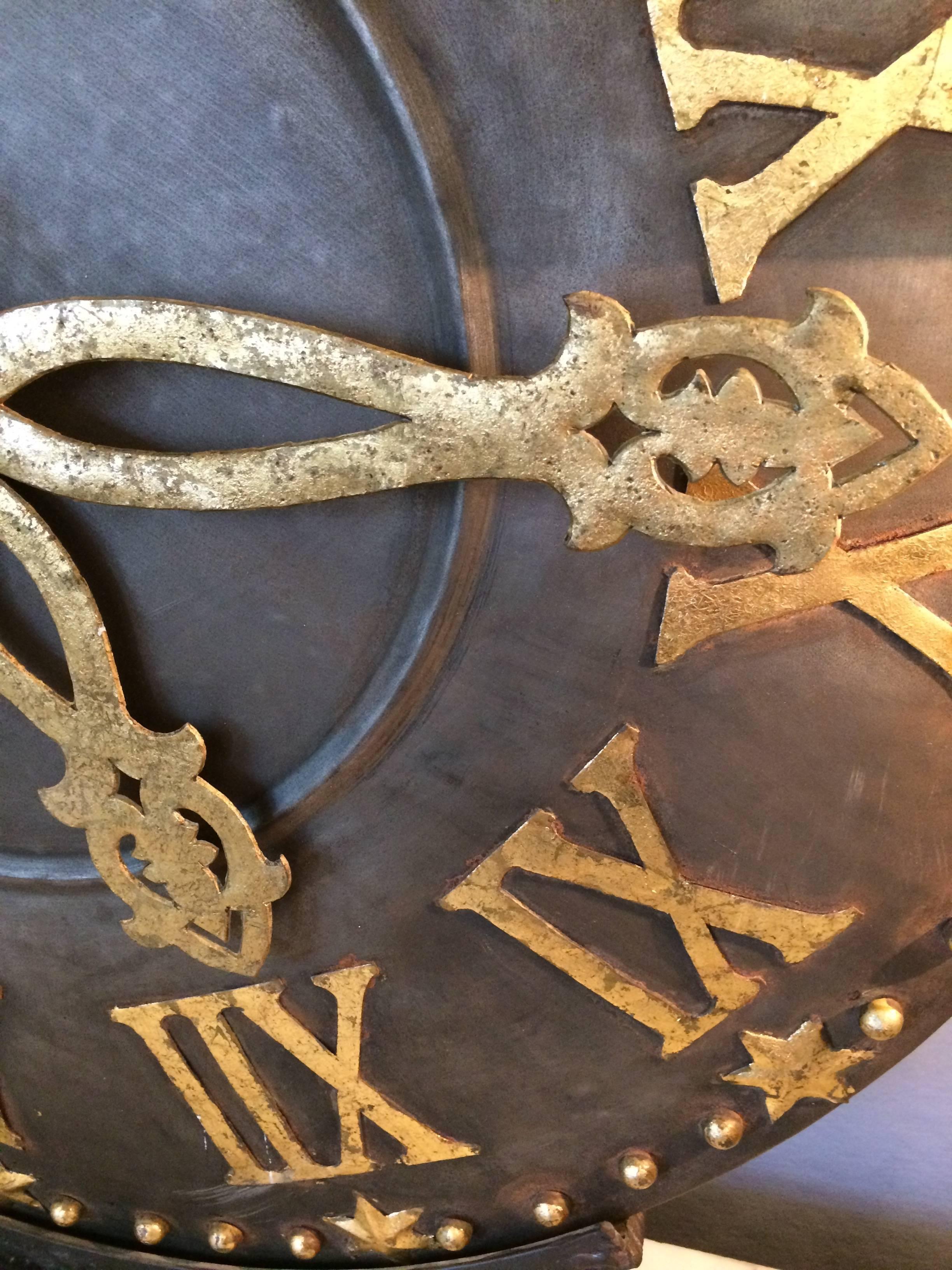 Large tabletop sculpture of a clock face in bold black iron with gold leafed Roman numerals. Base is 6 inches deep Decorative nonfunctional clock.