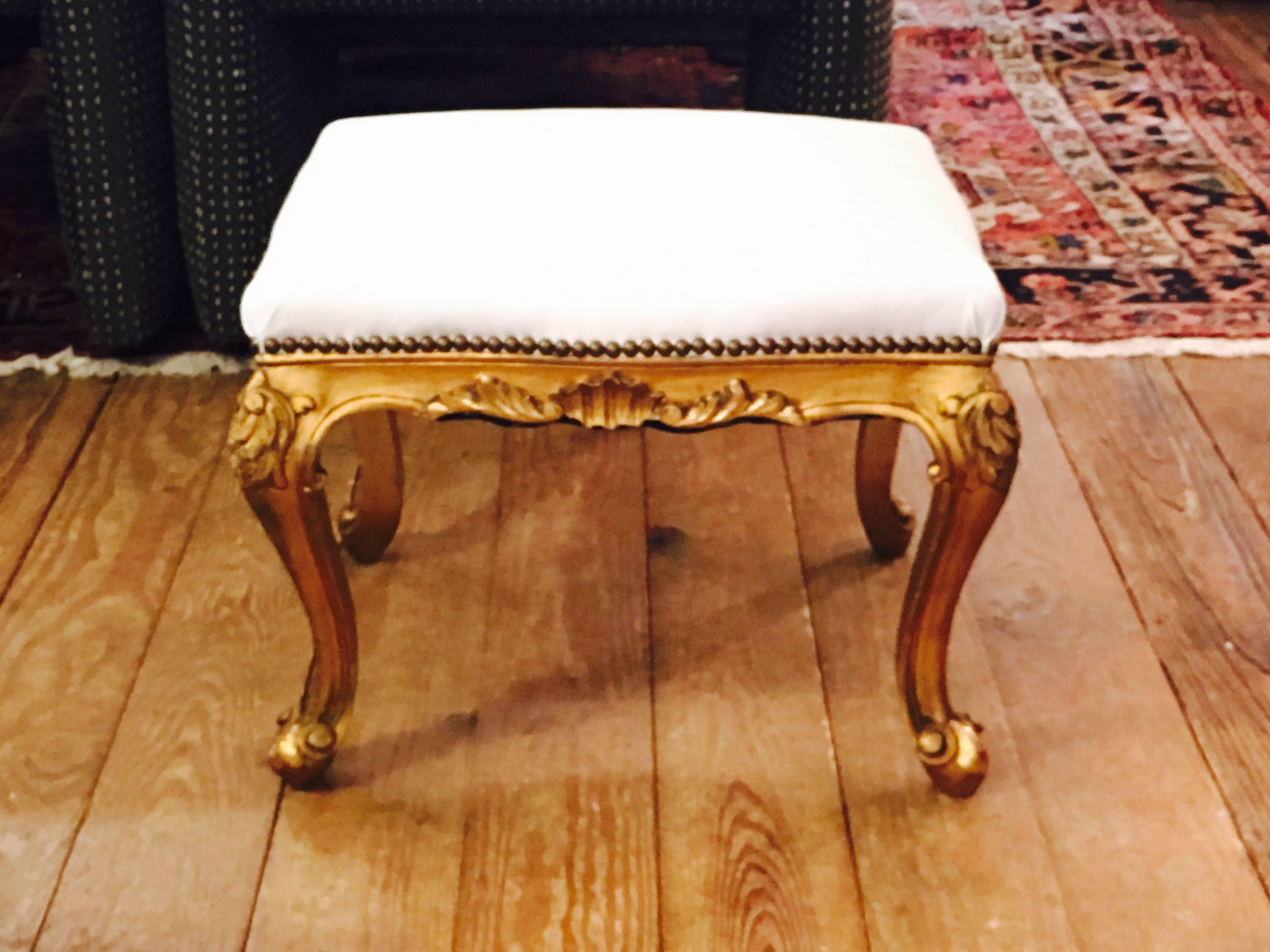 Two very elegant stools or small ottomans having fancy giltwood carved bases in Louis XVI style, and newly updated with creamy white leather tops.