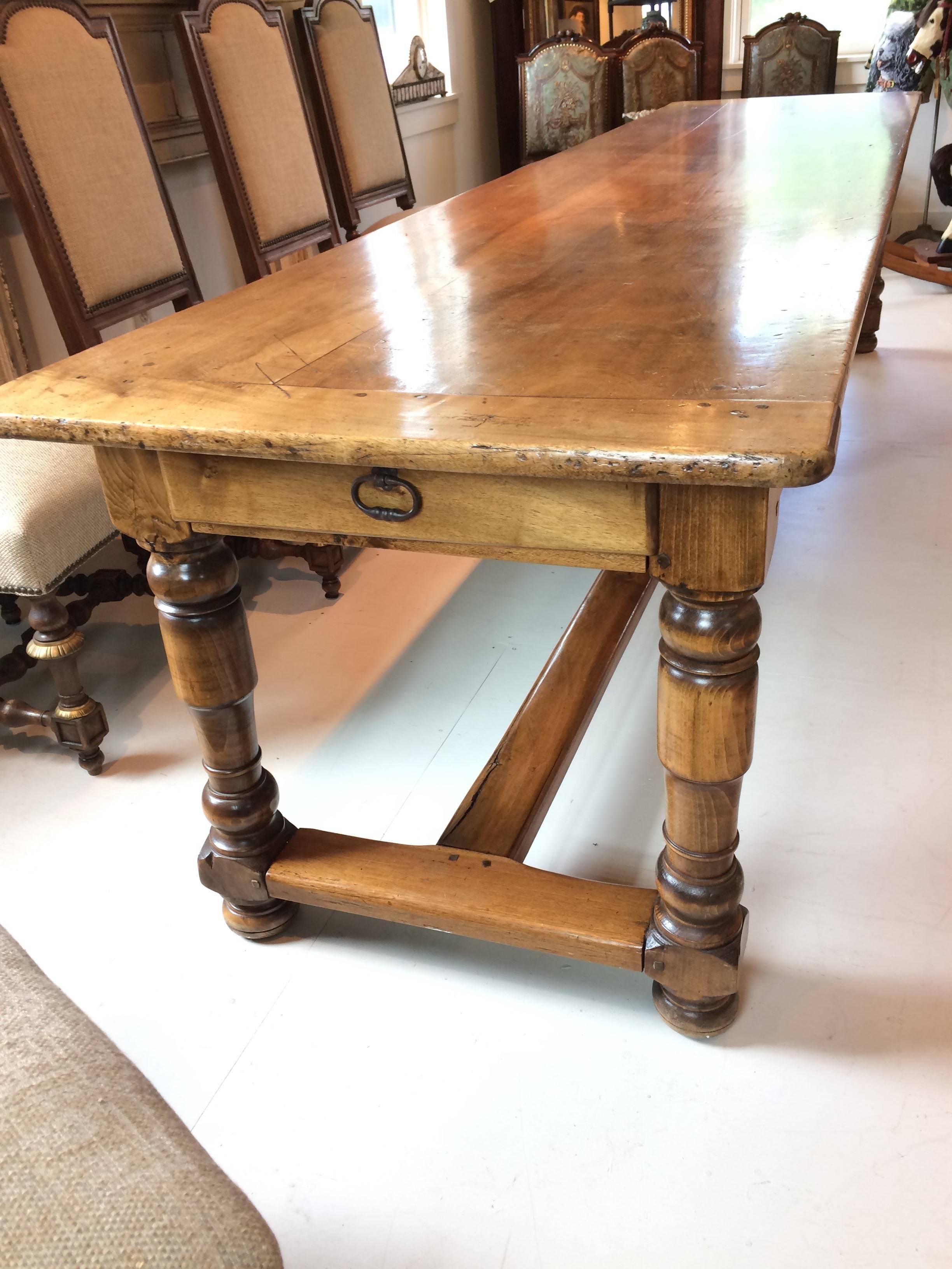 18th century French walnut refectory table from Isle-sur-la-Sorgue, France. This impressively long, elegant walnut table has a stretcher made with antique wood handsomely hand-carved legs and a drawer at each end. It's in excellent condition with a