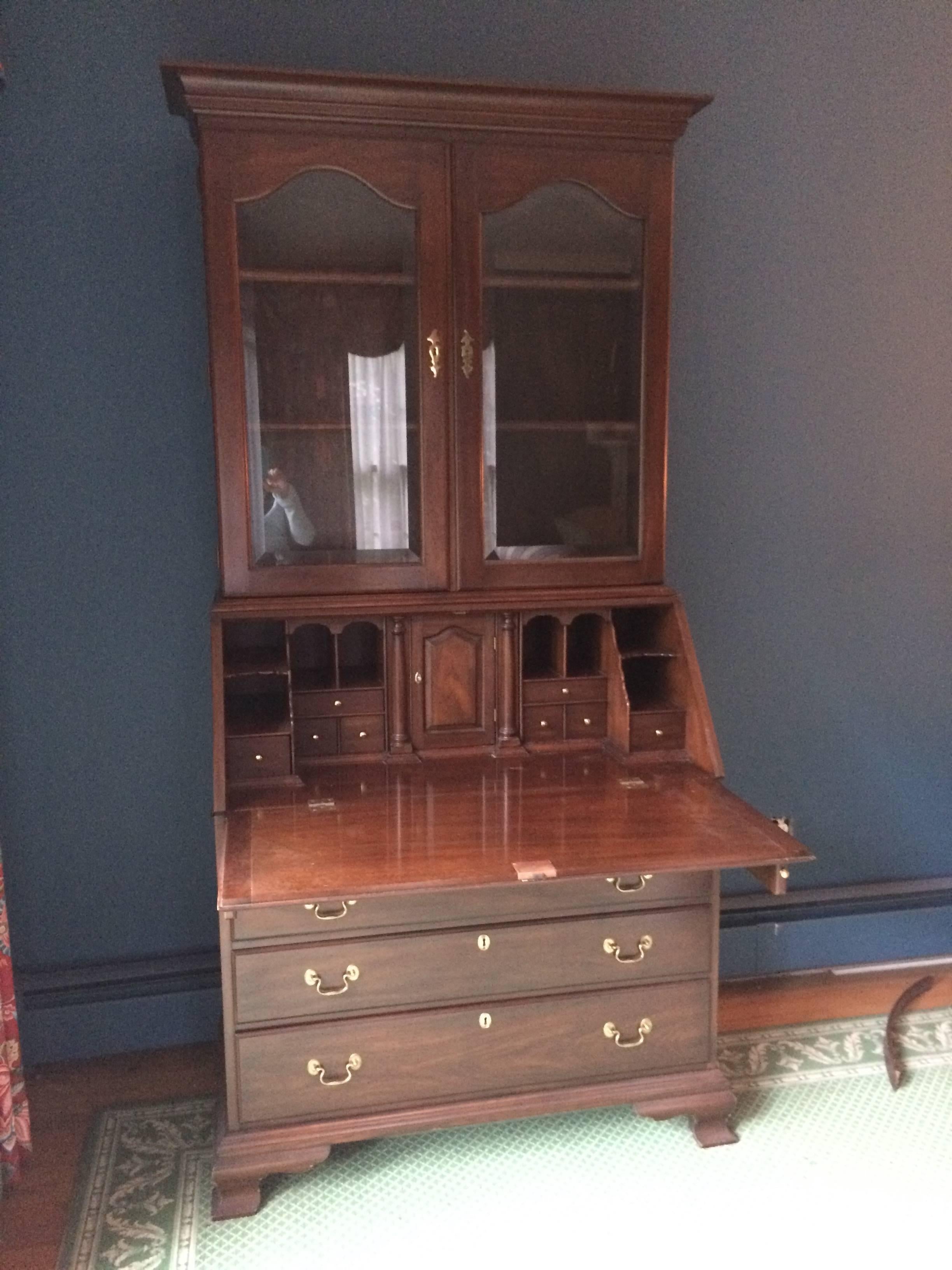 Traditional handsome mahogany two-piece chest on chest. Upper part has two glass doors and interior shelves, while the lower half has a pull-out desk surface and assorted cubbies on top of 4 roomy drawers. There's a nifty secret compartment in the