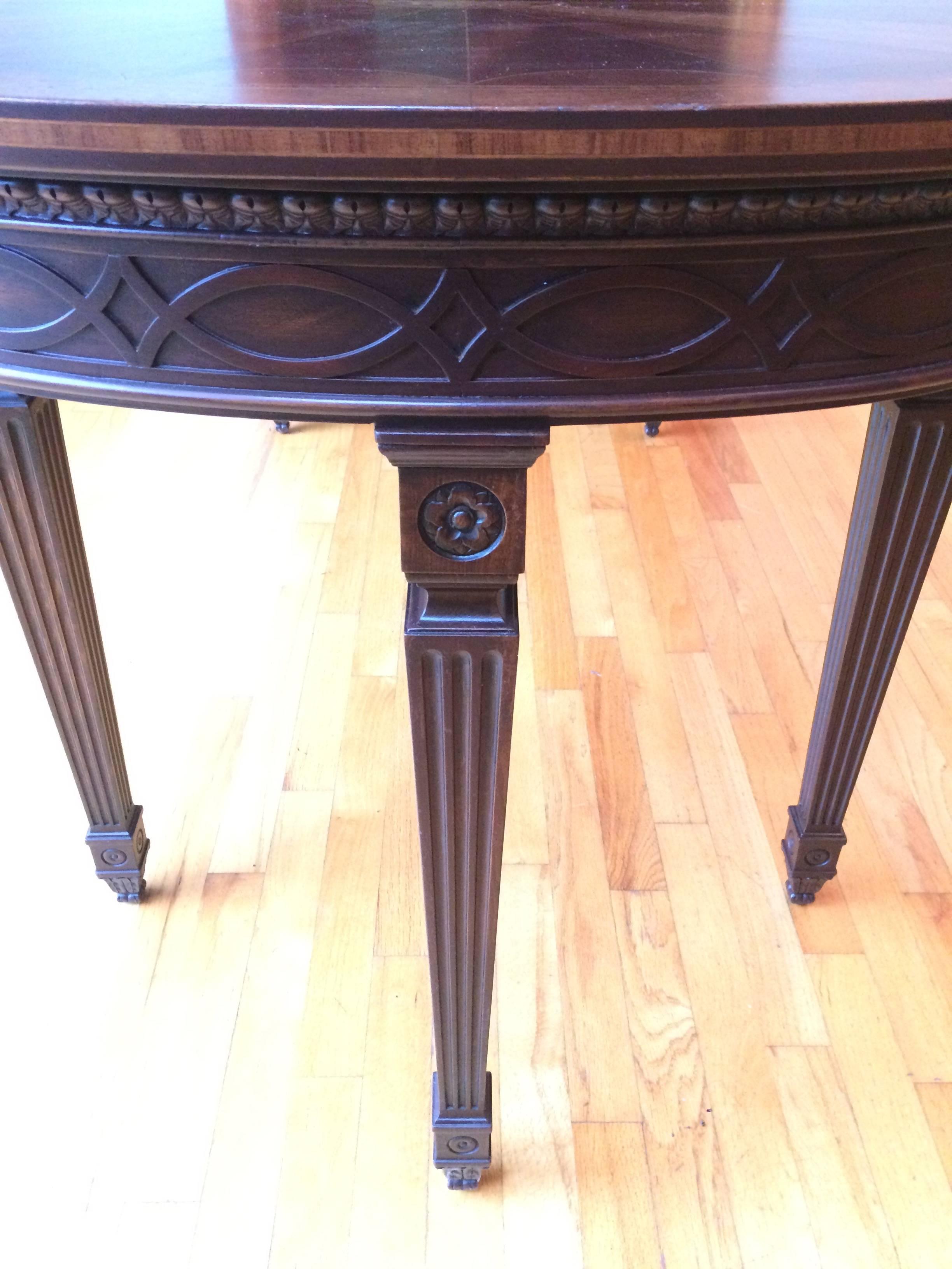 Very elegant and unusual long Regency style mahogany oblong marquetry inlaid table having beautiful carving in apron and lovely tapered reeded legs.  Apron is 25.25 H.
Can be used as a dining table, sofa back table, library table, etc.