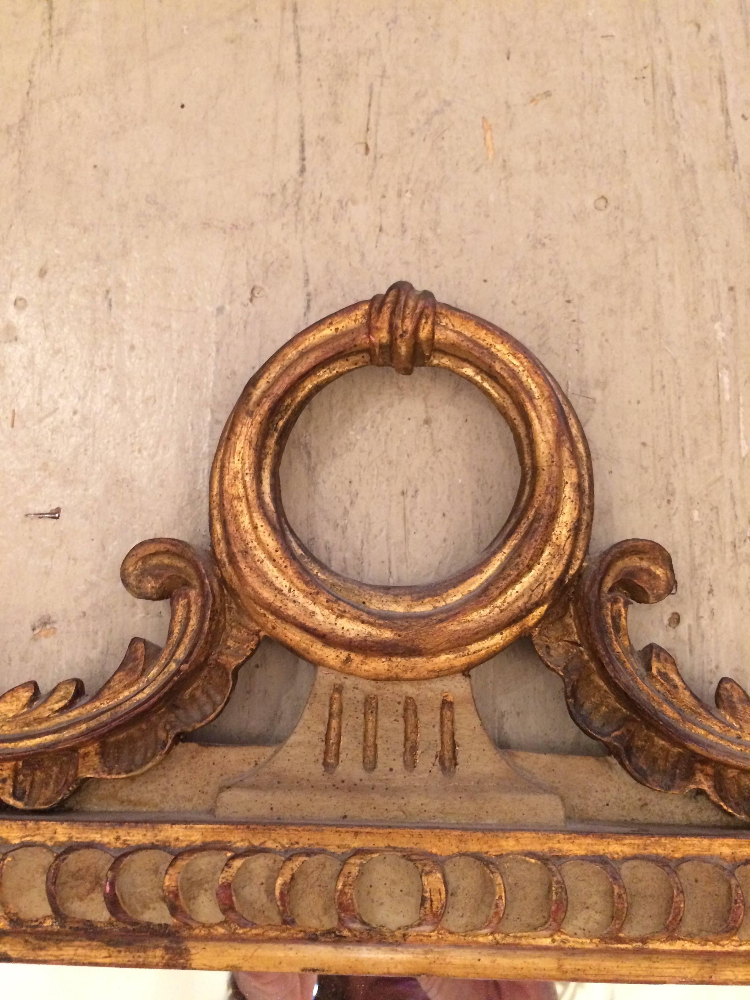 Pretty vertical rectangular mirror by Palladio, Made in Italy, having a carved painted and gilded wood frame with circle and curlicues at the top.