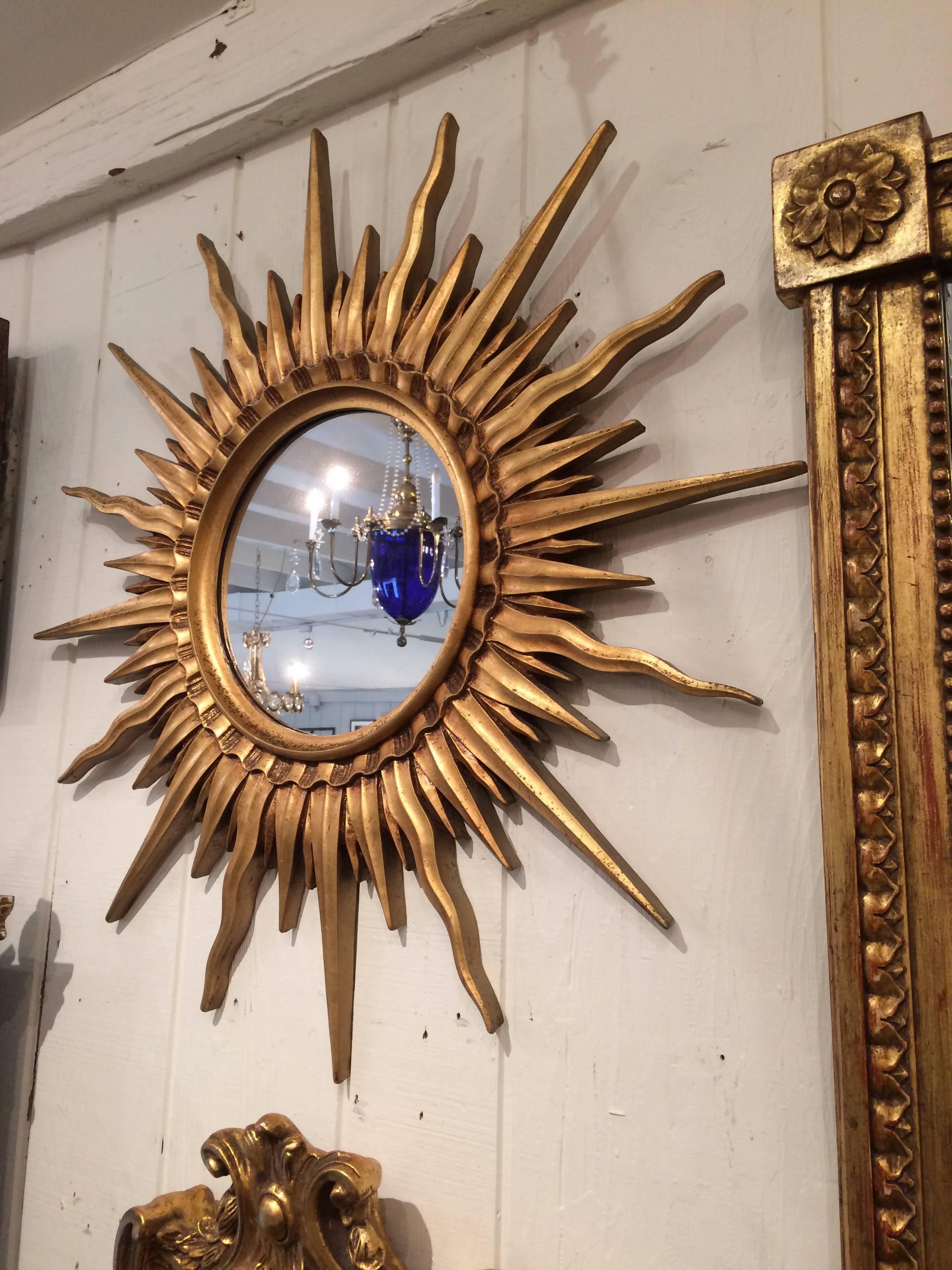 Stylish composition wood that has been gilded in a stunning sunburst shape to surround a round mirror by Mario Buatta.
