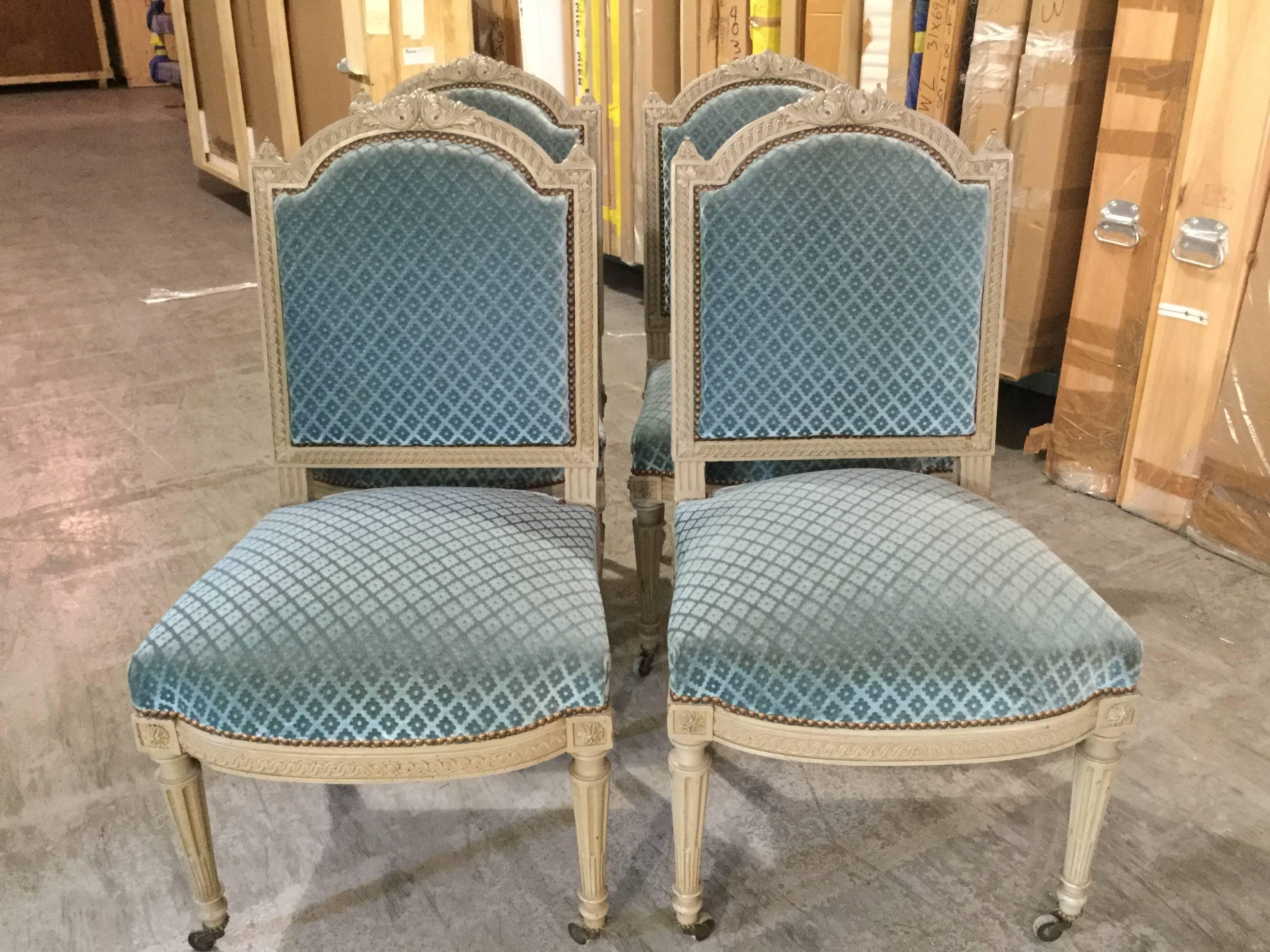 Set of four painted Louis XVI-style velvet chairs. Beautifully carved frames retain the original dove grey paint. Upholstered in a diamond pattern blue velvet, circa 1920s.
Seats could use some updated springs.  Afew rosettes missing.
 