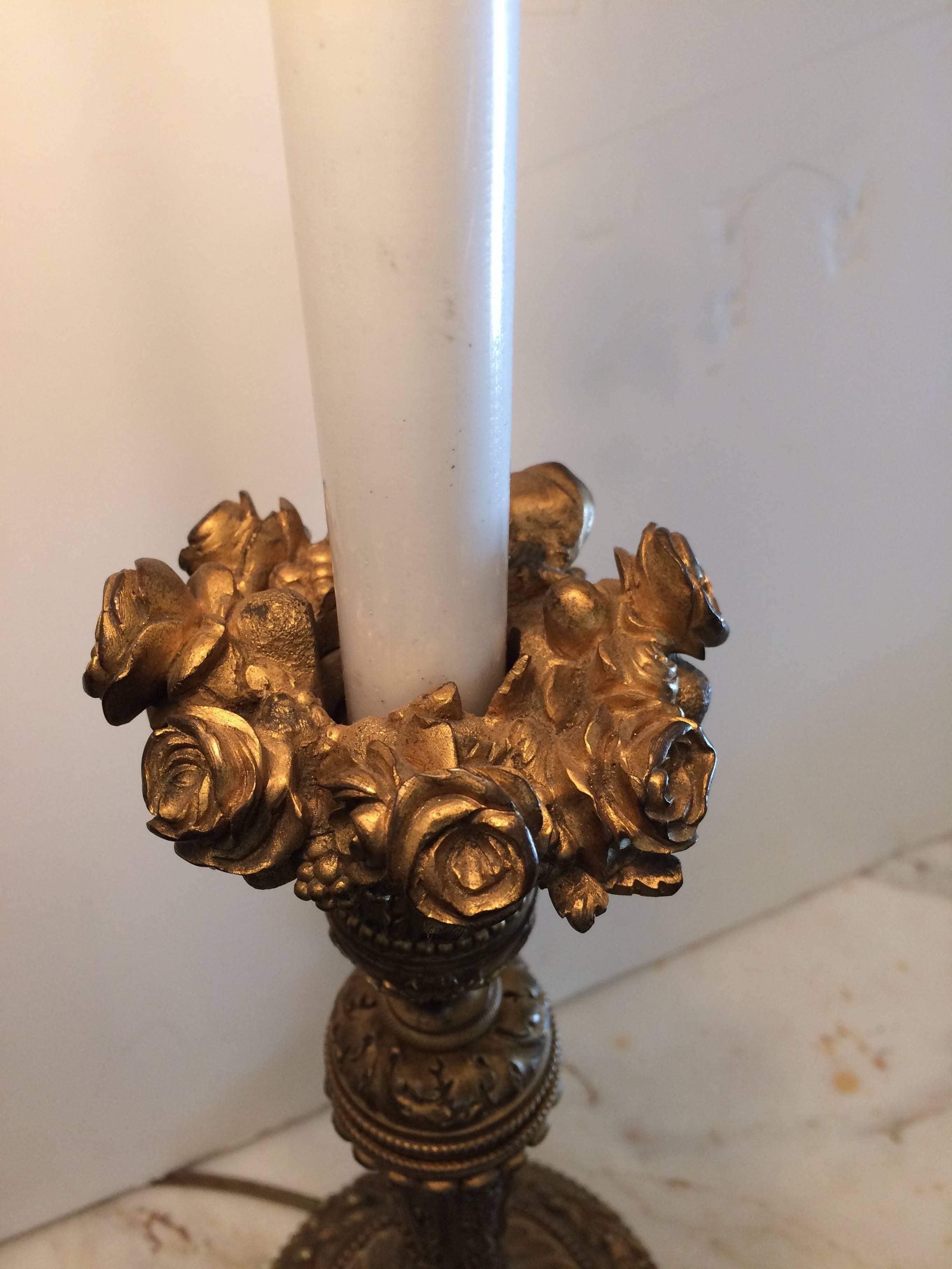 Romantic bronze candlestick lamp having ornate roses in a circle at the top and gorgeous decoration overall, topped with a wonderful tole lampshade and acorn finial with arrow.