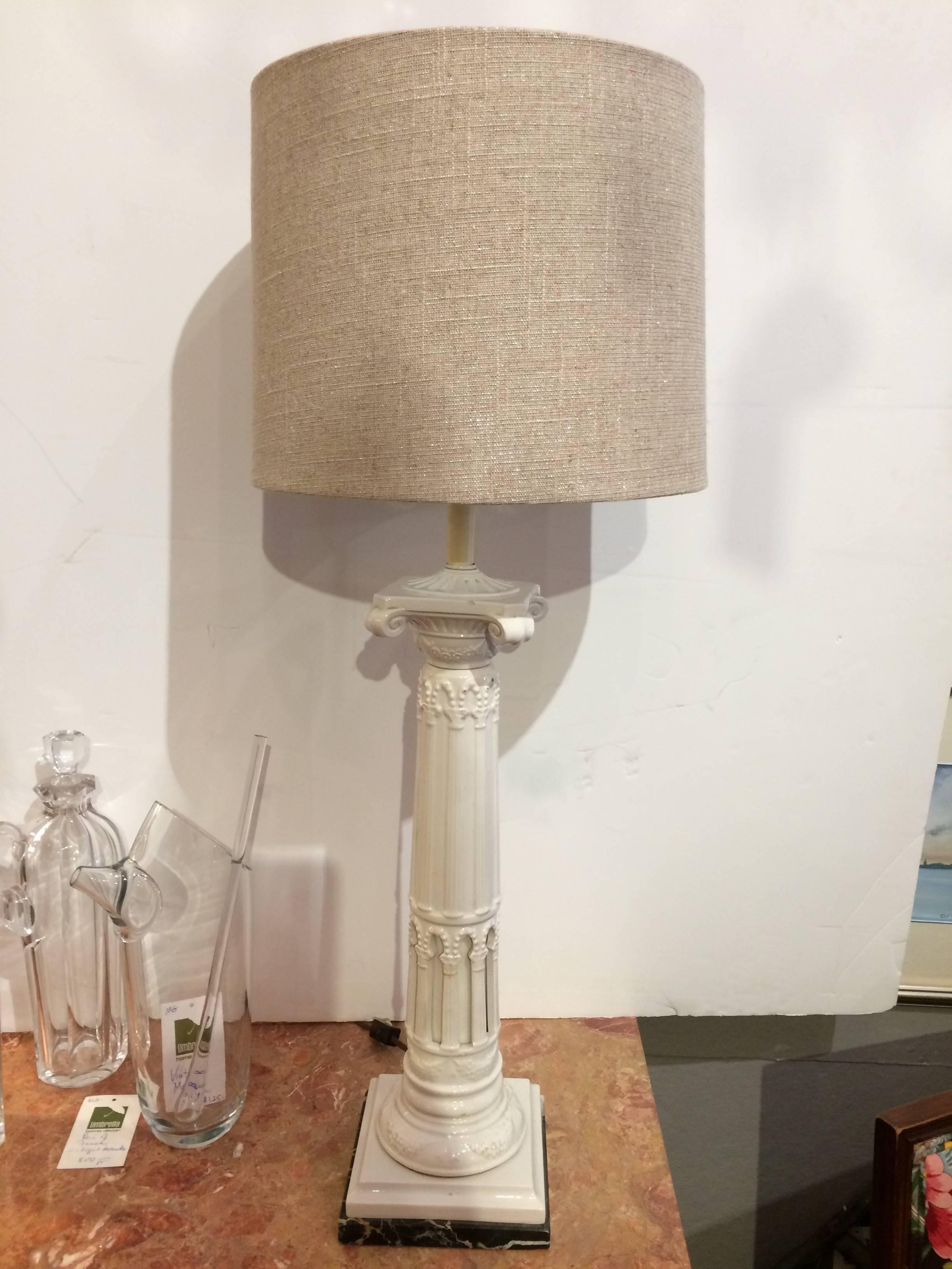 Two handsome lamps having ceramic off-white columns with intricate detailing that sit on black and cream marble bases. Custom linen shades and one socket. Base is 6 in square.