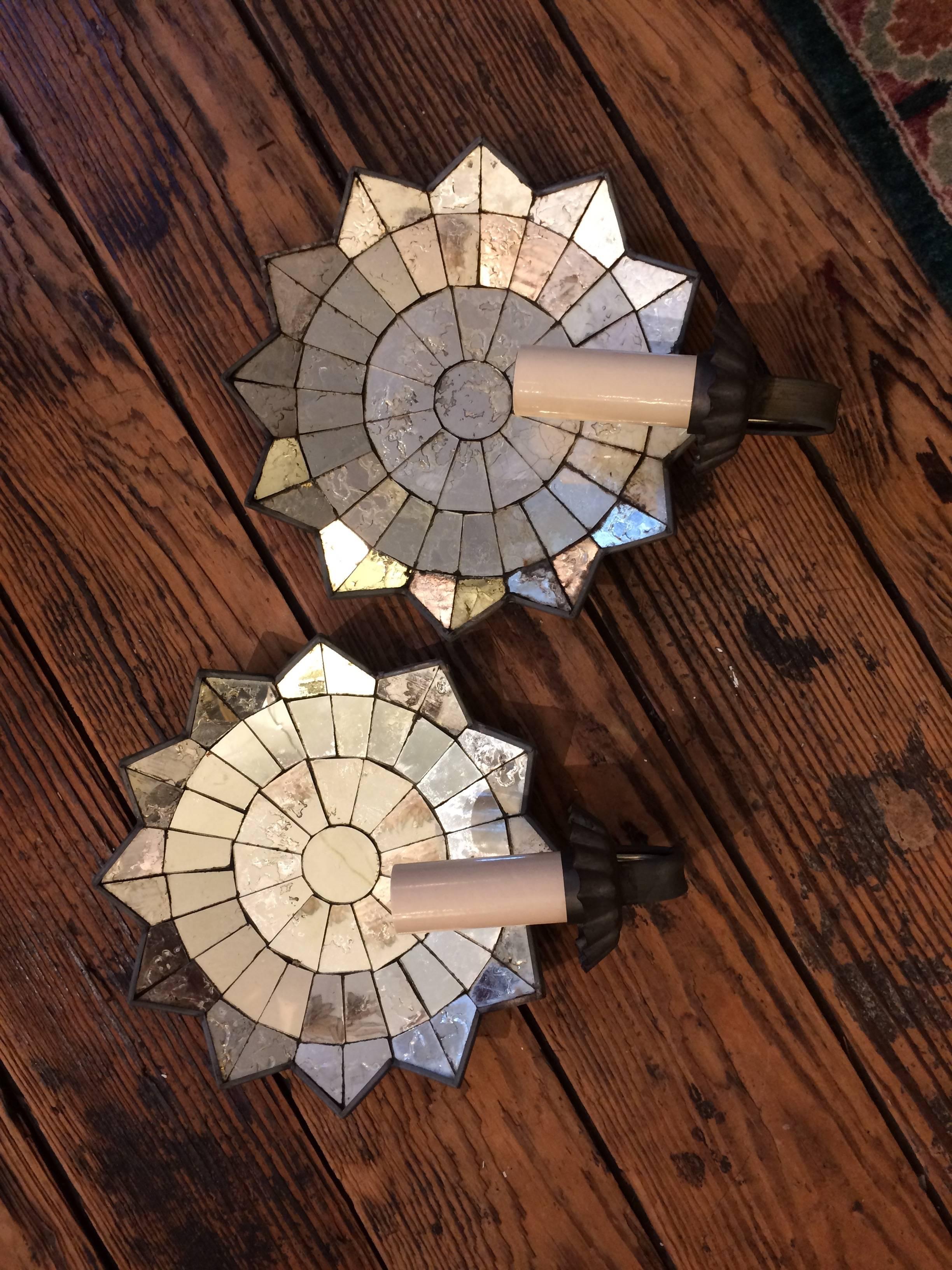 Two round glamorous wall sconces with antique mirrored star like backs and matte metal candle holders. Newly electrified.