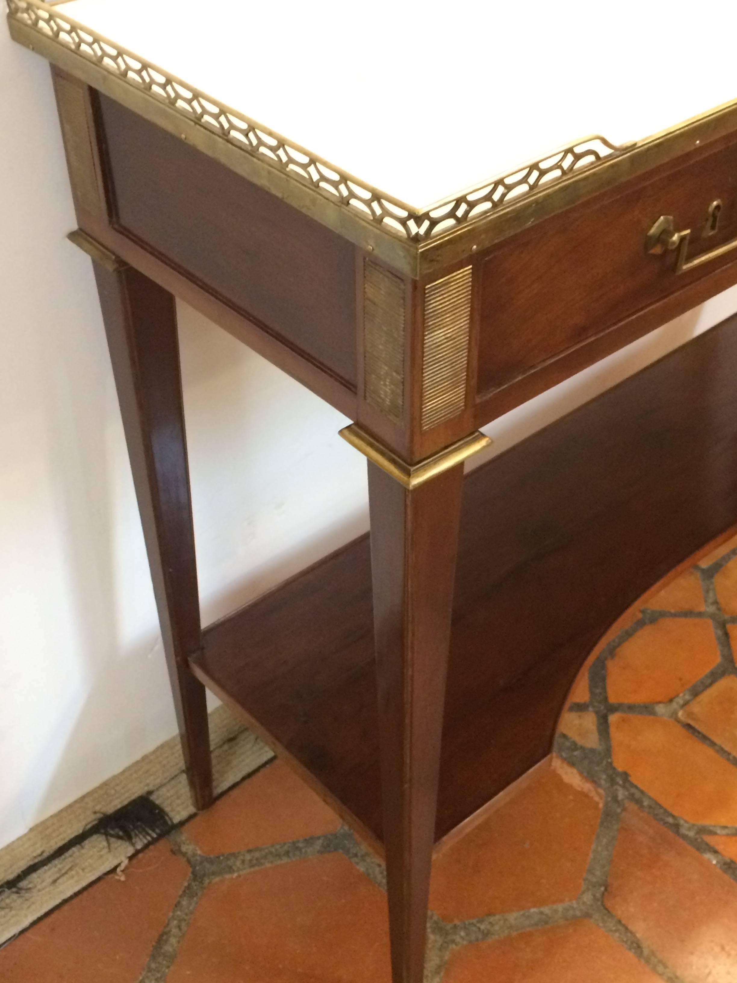 Very elegant antique console having bronze gallery and hardware, constructed of lovely rich mahogany with bottom tier and tapered legs, topped with Classic off-white marble with grey veining.