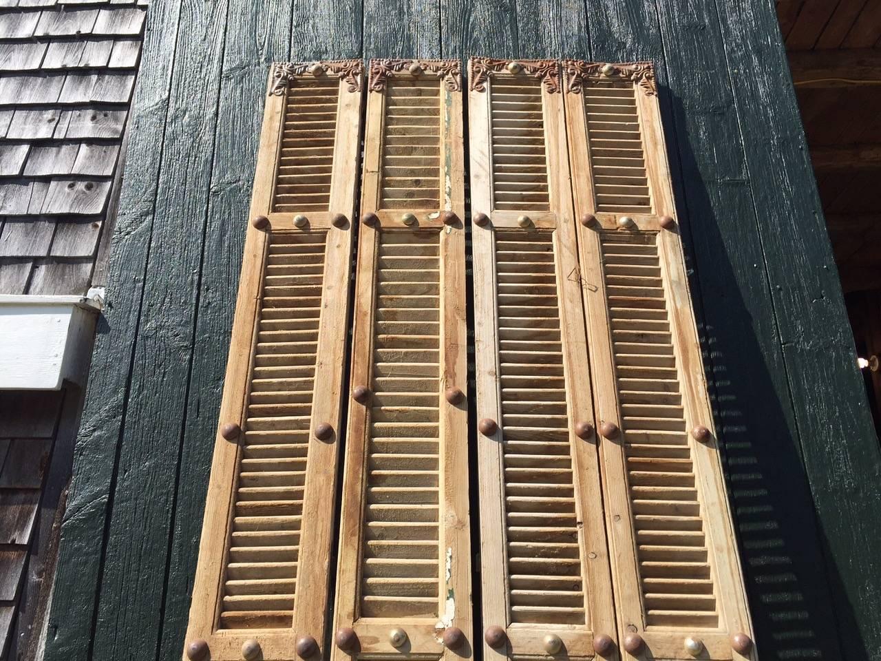 Two pairs of wonderful very tall elongated French shutters with lovely decorative metal embellishments and interesting raised bumps that are metal ornamentation. The wood is natural and unpainted. The metal décor is unusual and gorgeous. Bought in