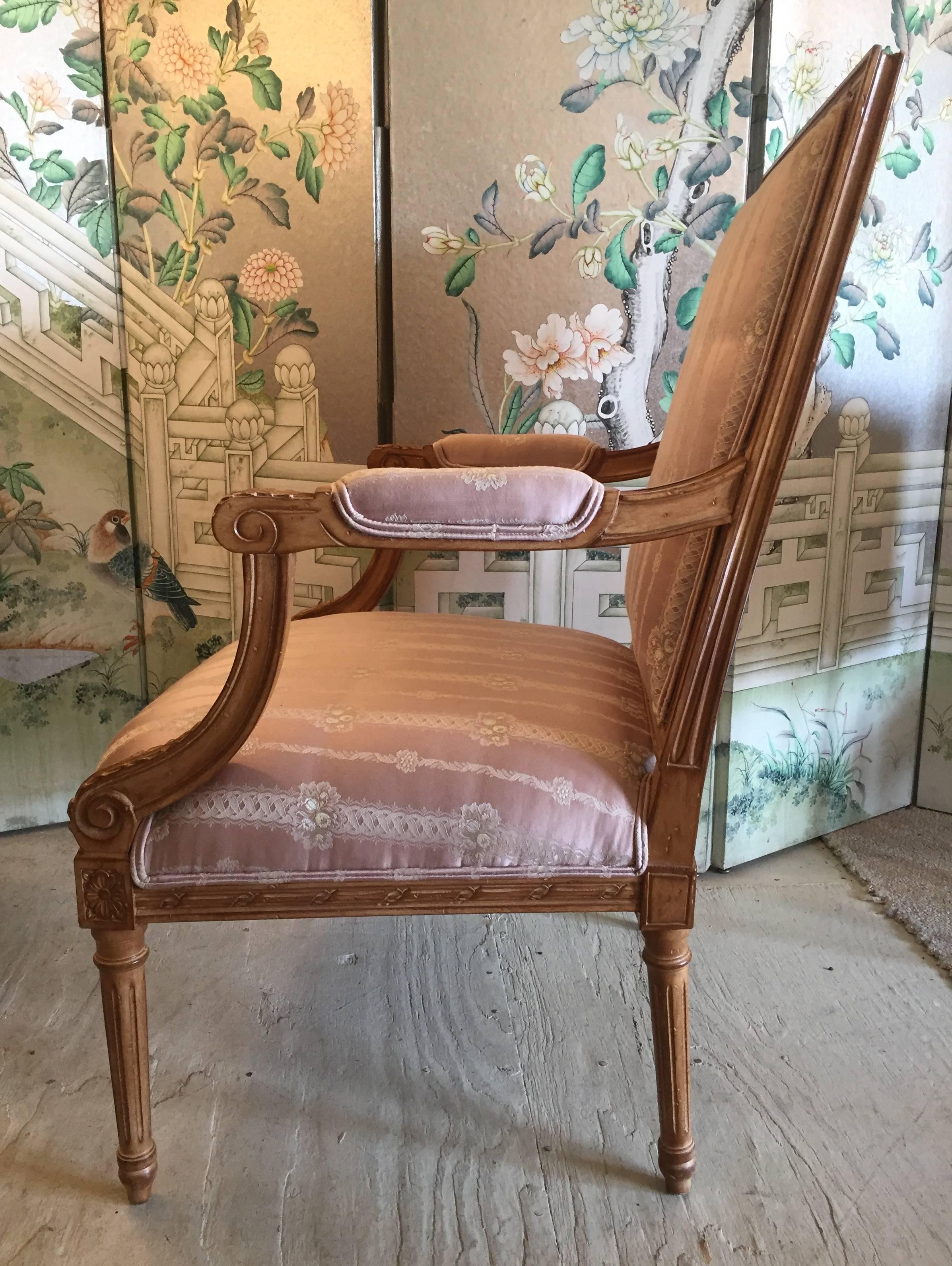 Elegant French armchairs having carved walnut frames and upholstered in a rose silk fabric.
 