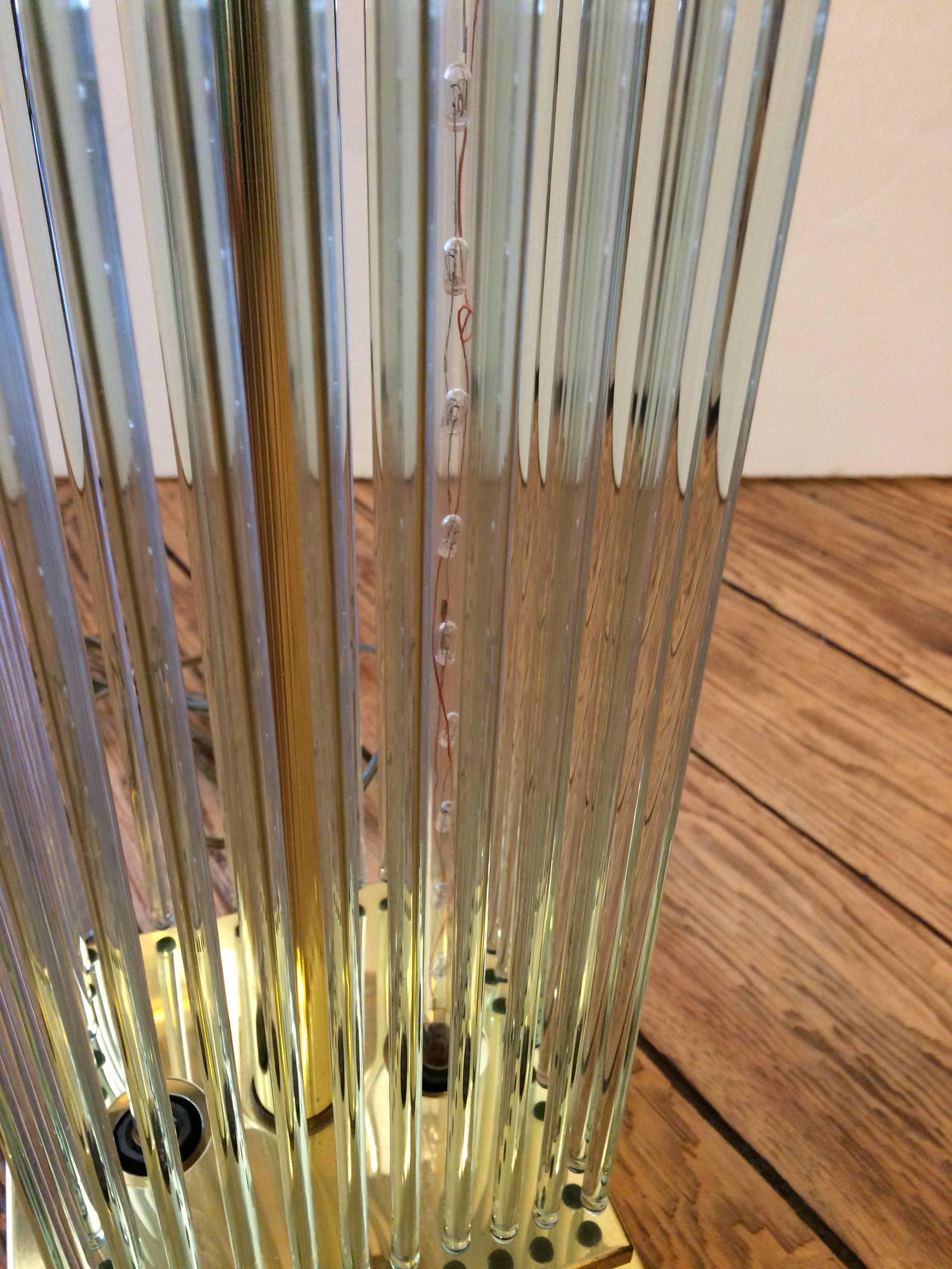 Out of the ordinary glitzy Mid-Century Modern lamp having a cool base with a collection of hanging narrow glass rods. Lights up in two places, inside and on top.
Base is 7 x 7.