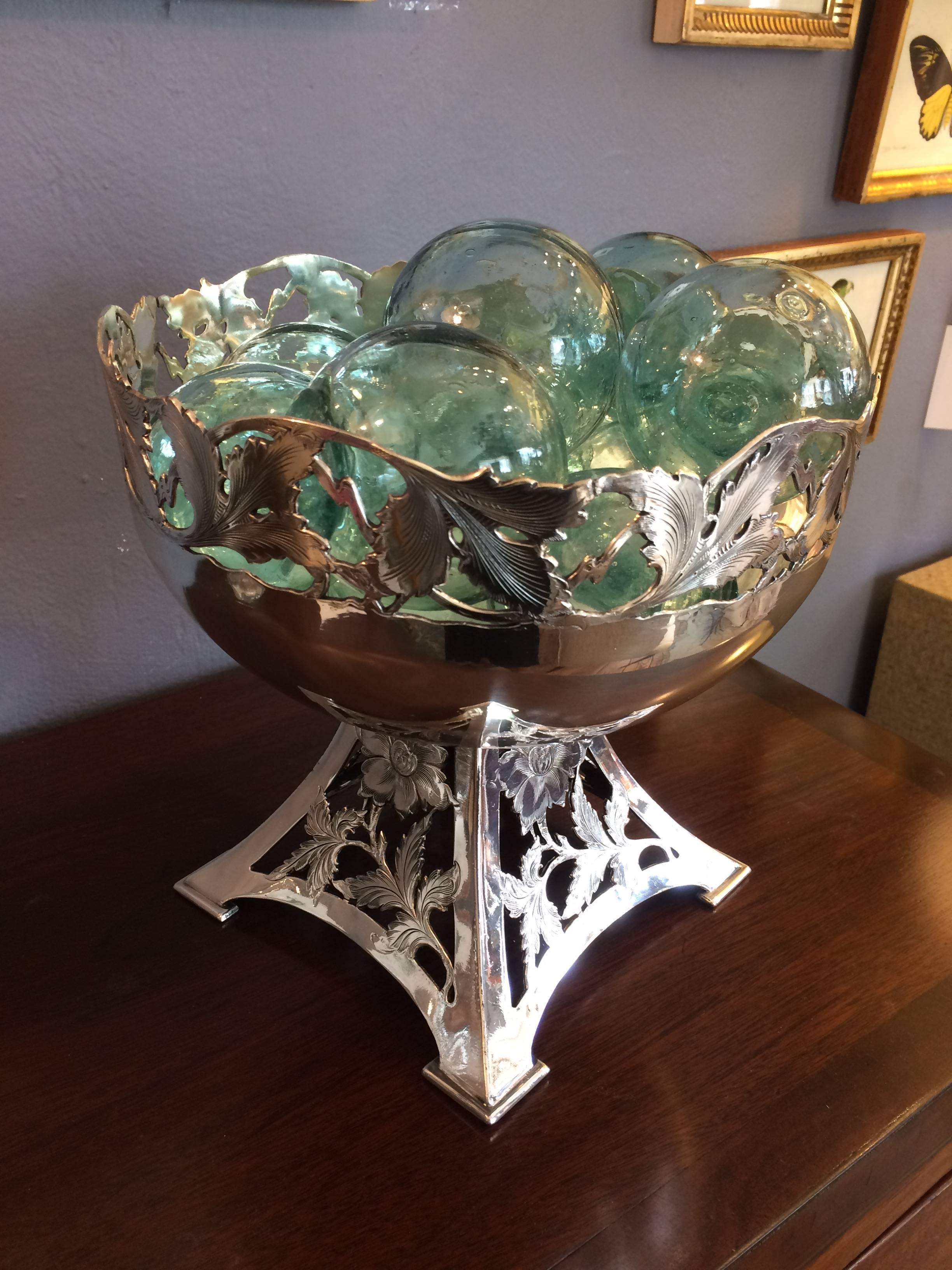Lovely decorative silver plate compote with beautiful workmanship. It's been lacquered so won't tarnish. Pretty collection of light aqua glass floaters are included.